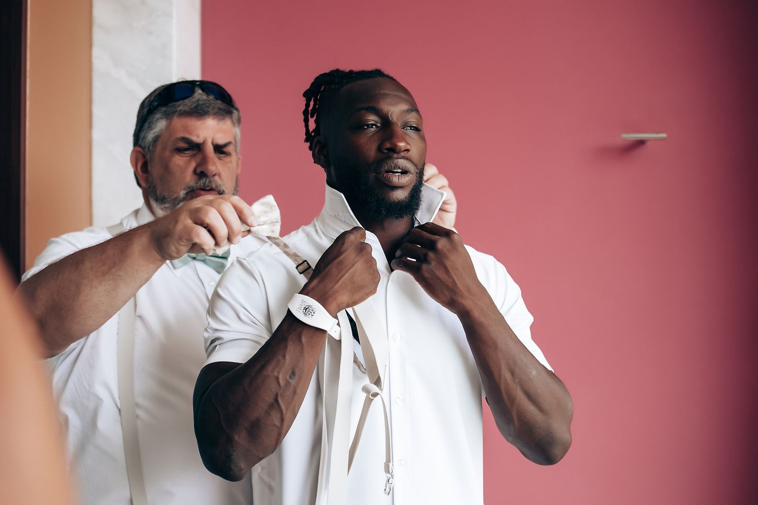 Two people in white shirts dancing against a pink backdrop.
