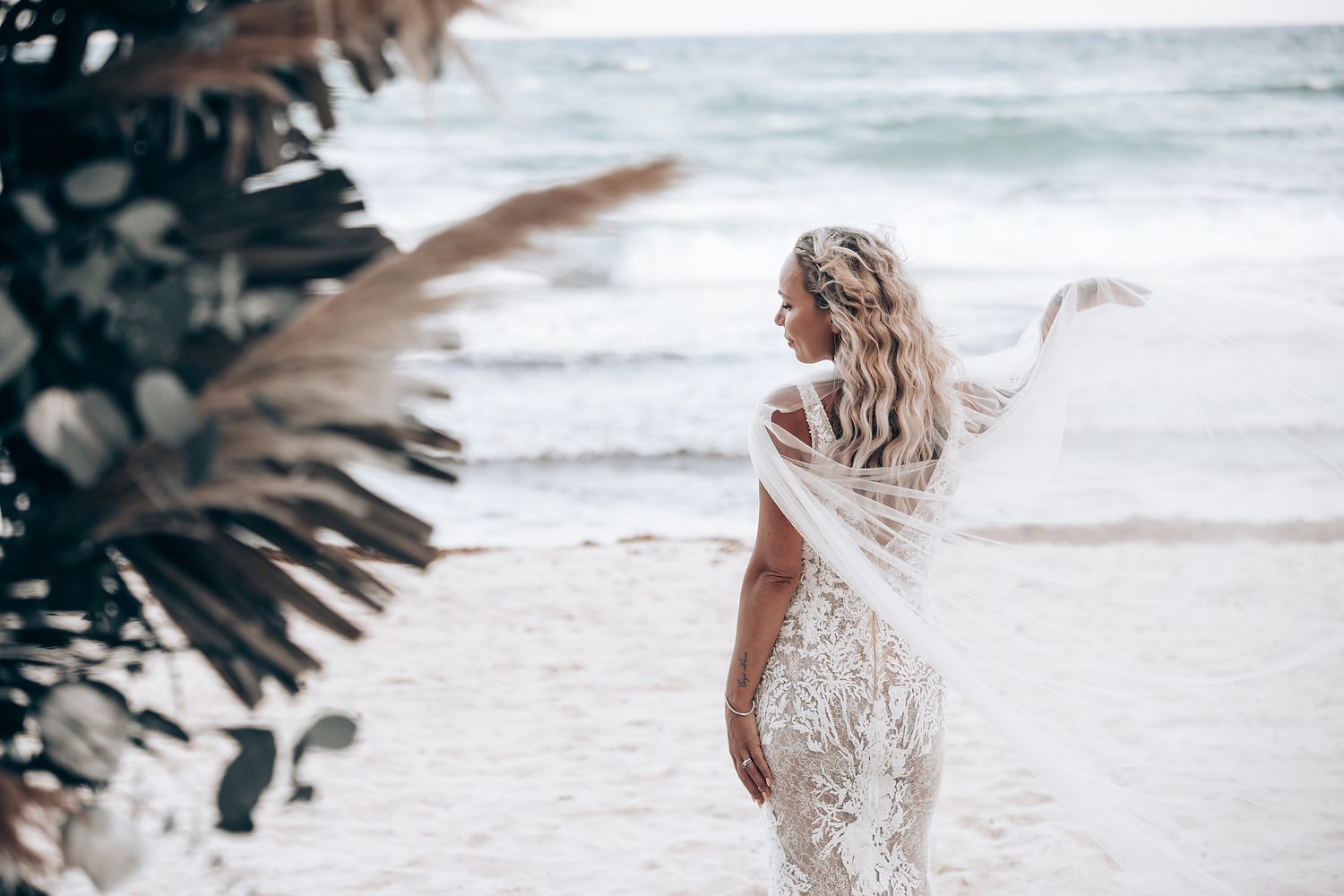 Beachside wedding celebration with decorative floral arrangements and waves crashing in the distance.