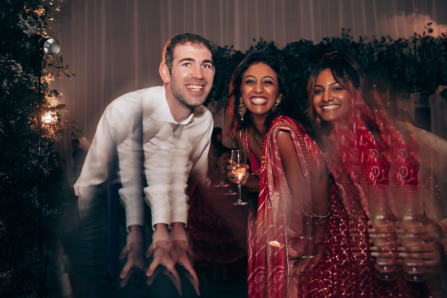Wedding party dancing and celebrating in a dimly lit reception venue.
