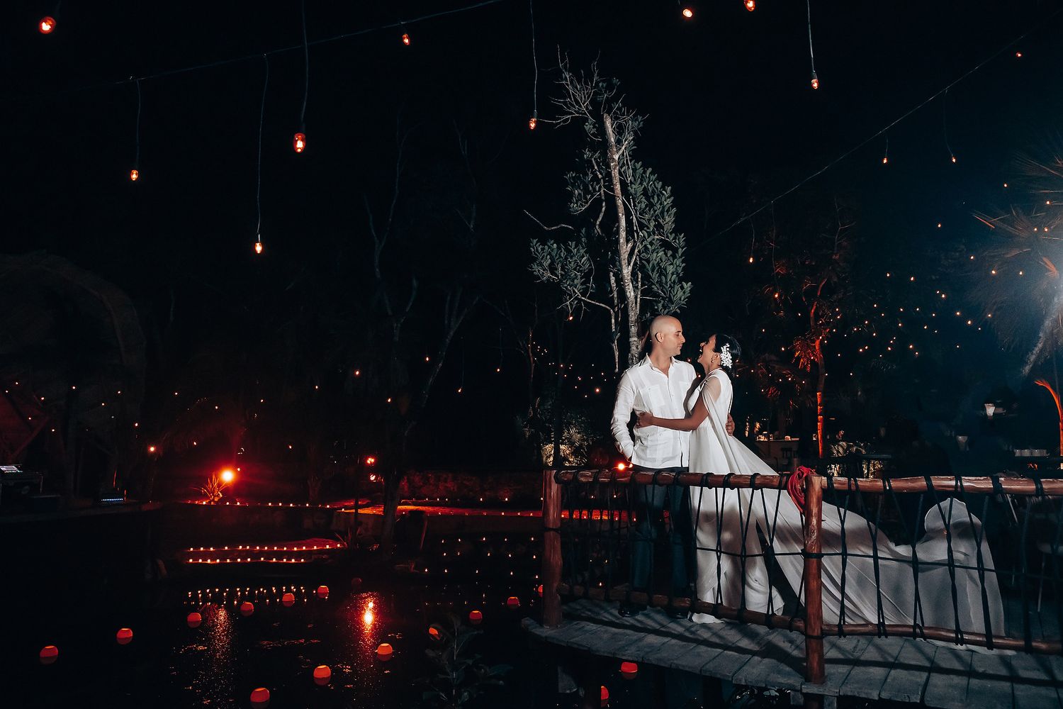 Wedding celebration at night with red lights and sparklers creating a romantic ambiance.