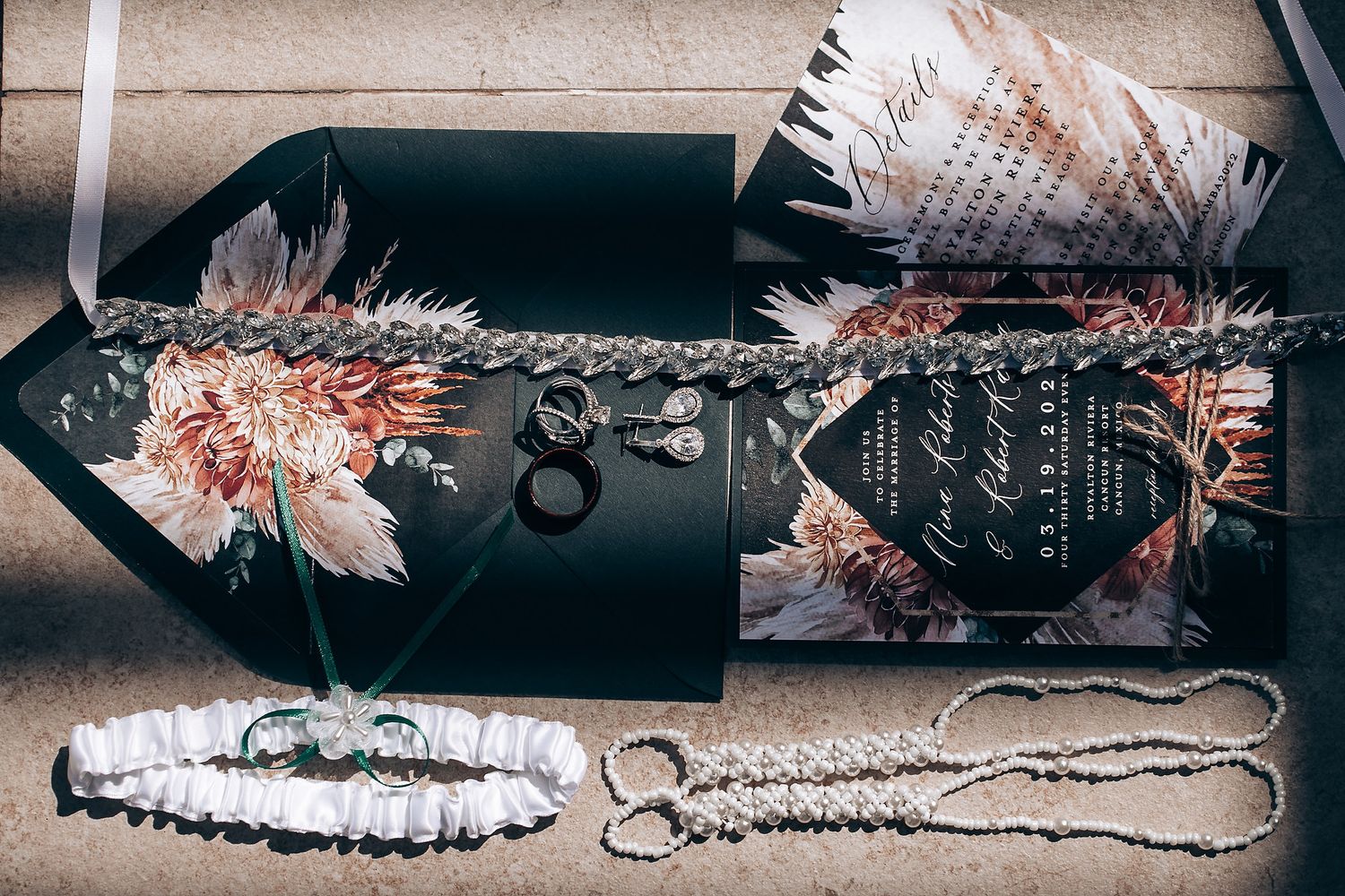 Close-up details of delicate lace and beaded wedding dress accessories laid out in a row.