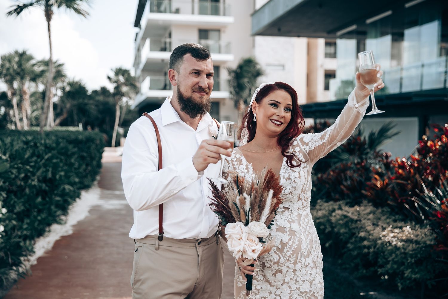 Couple celebrating at a tropical destination wedding with palm trees in background.
