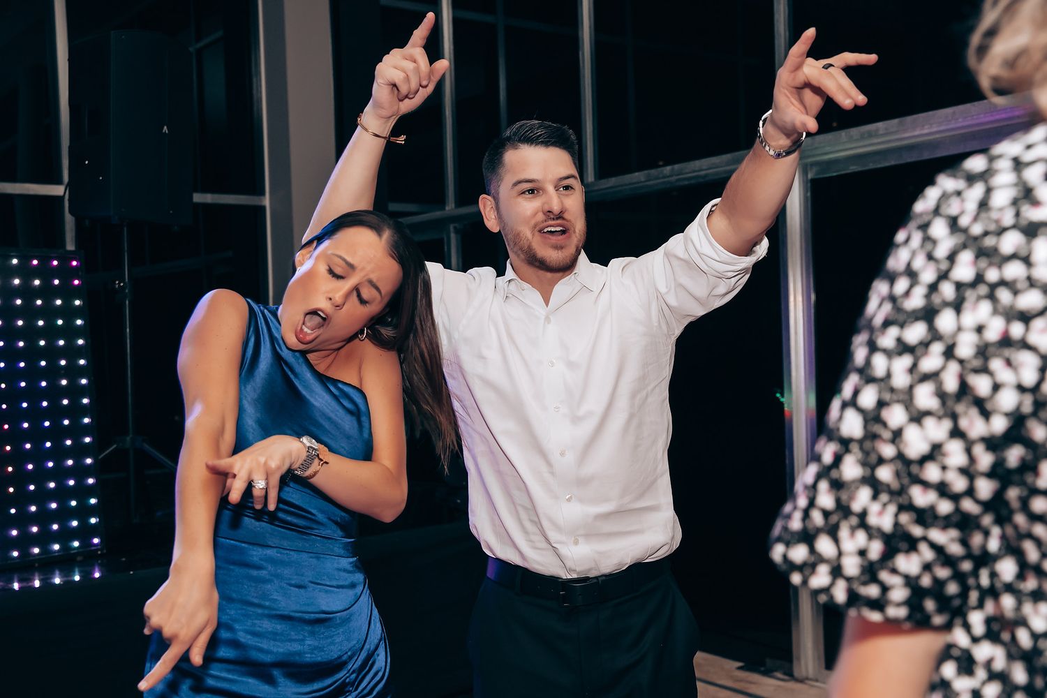 Wedding reception guests dancing and celebrating with enthusiasm at a nighttime party.