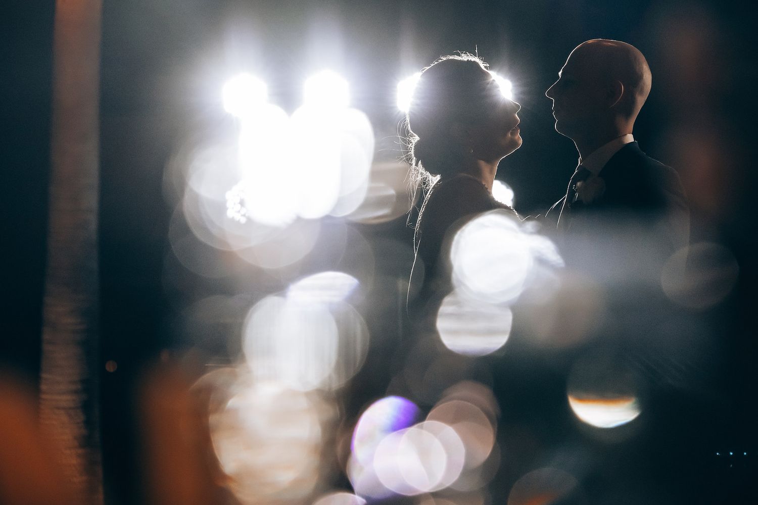Blurred lights and silhouettes of people at what appears to be a wedding reception or event.