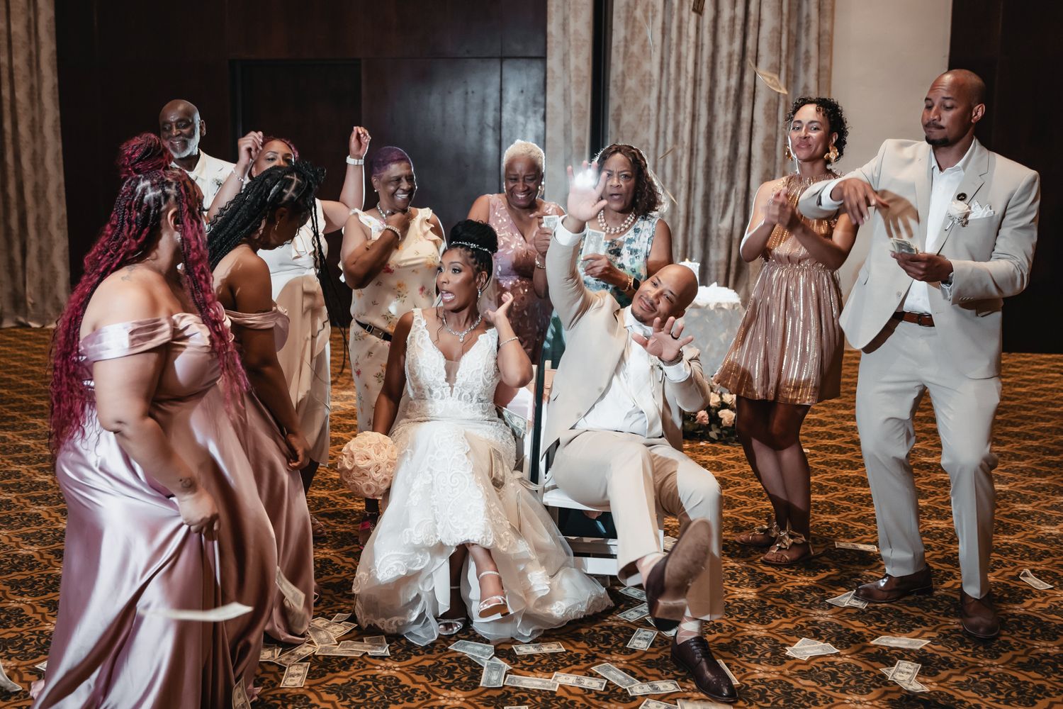 Joyful wedding party celebration with bride in white gown, bridesmaids in pink, and groomsmen in white suits dancing.