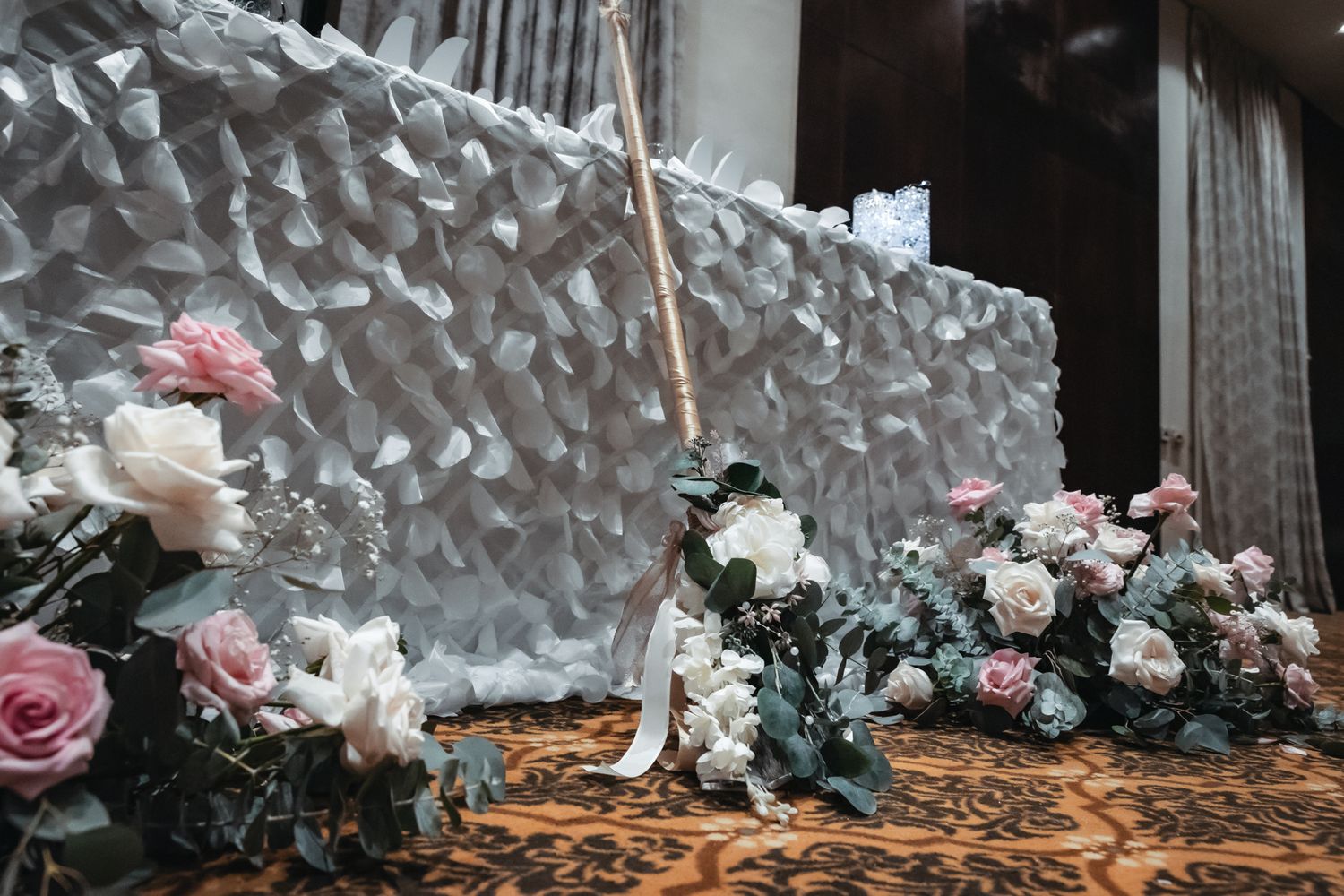 Elegant wedding backdrop with white 3D floral wall decor and pink and white rose arrangements on the floor.