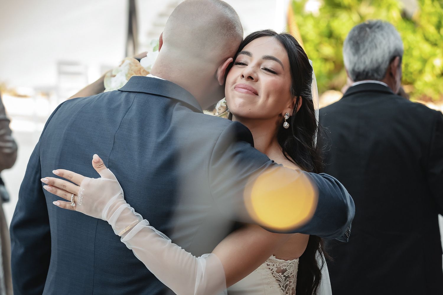 Bride and groom share a romantic embrace and kiss at their wedding ceremony outdoors.