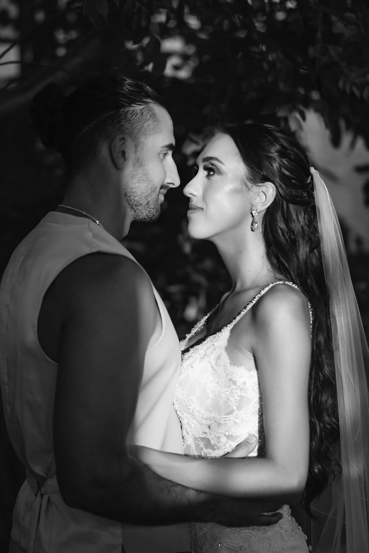 Black and white wedding portrait of bride and groom gazing at each other outdoors.