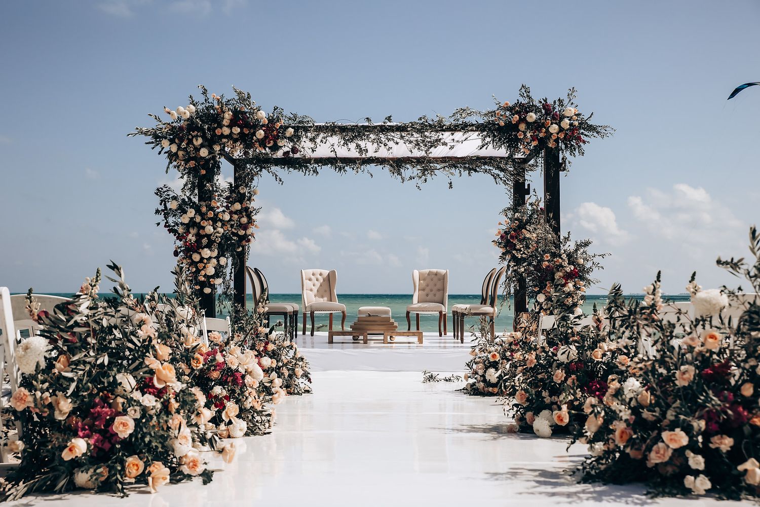 Elegant floral arch setup for beach wedding ceremony with ocean view.