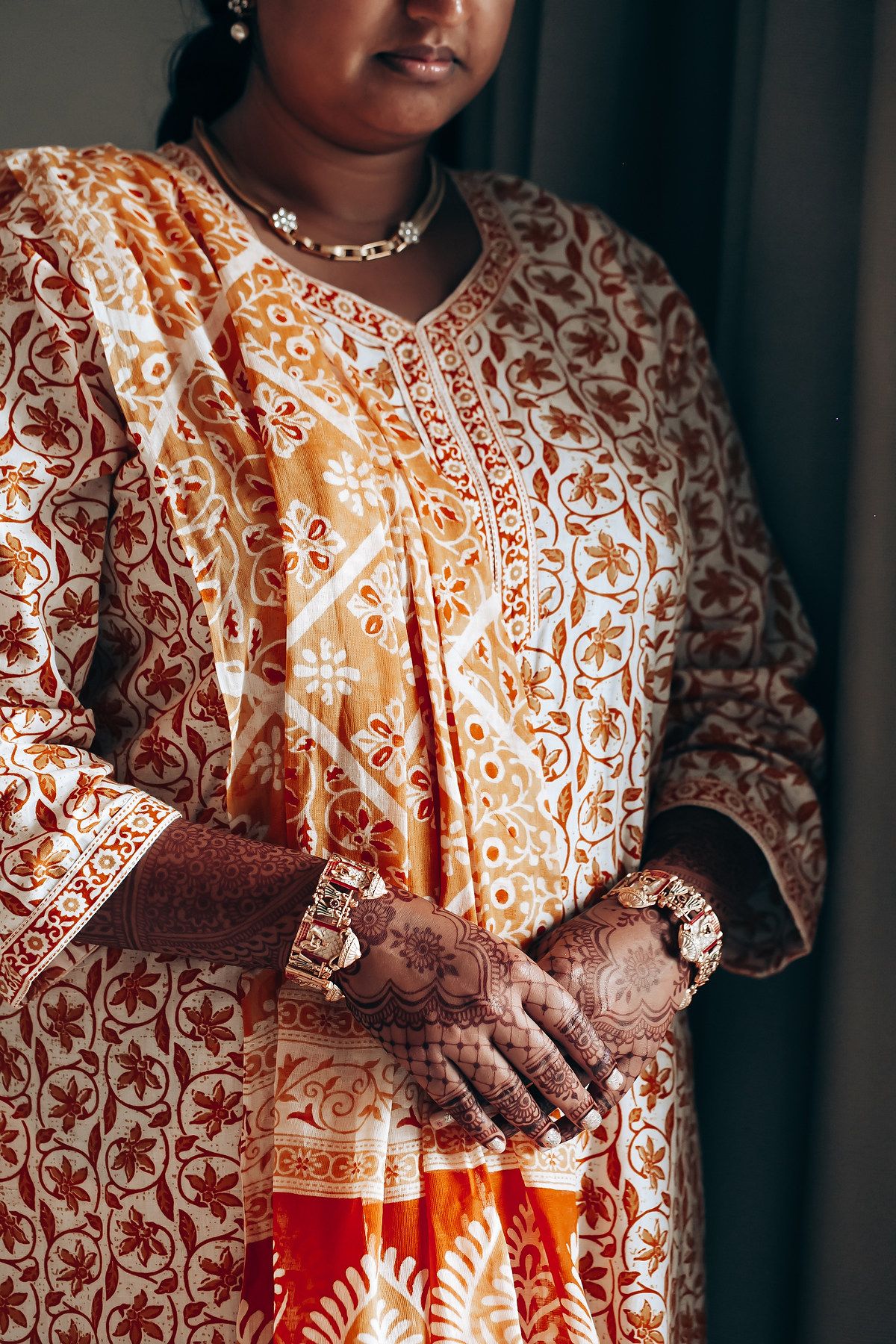 Intricate details of traditional Indian wedding attire with orange and white embroidered patterns.