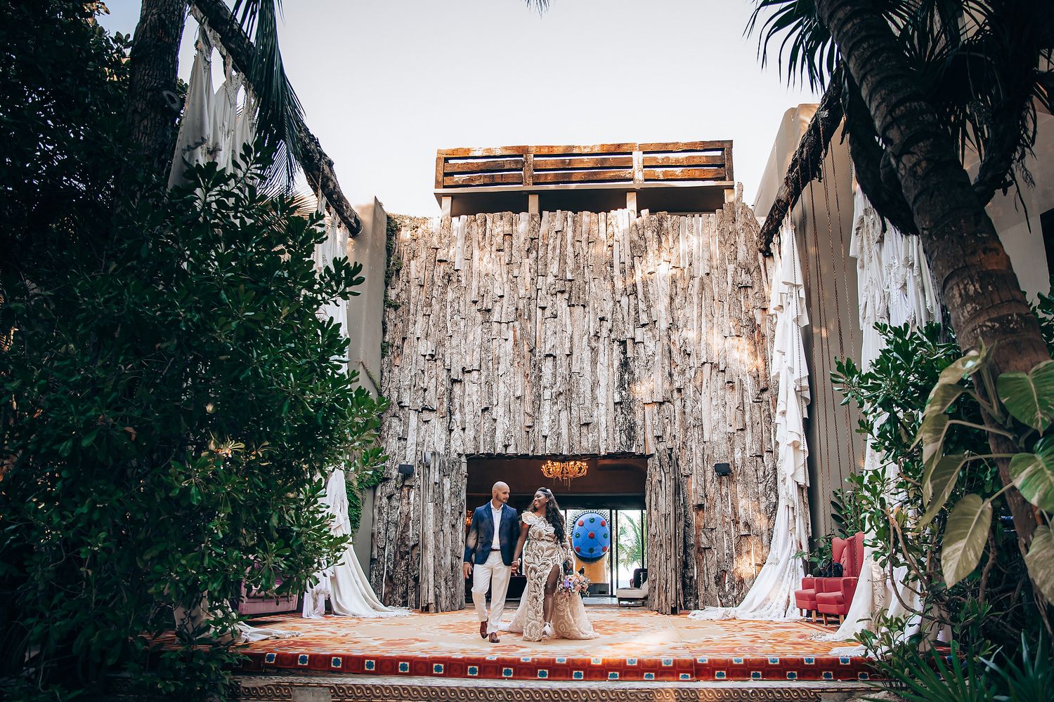 A rustic outdoor wedding ceremony setup with wooden benches and white fabric draping in a garden setting.
