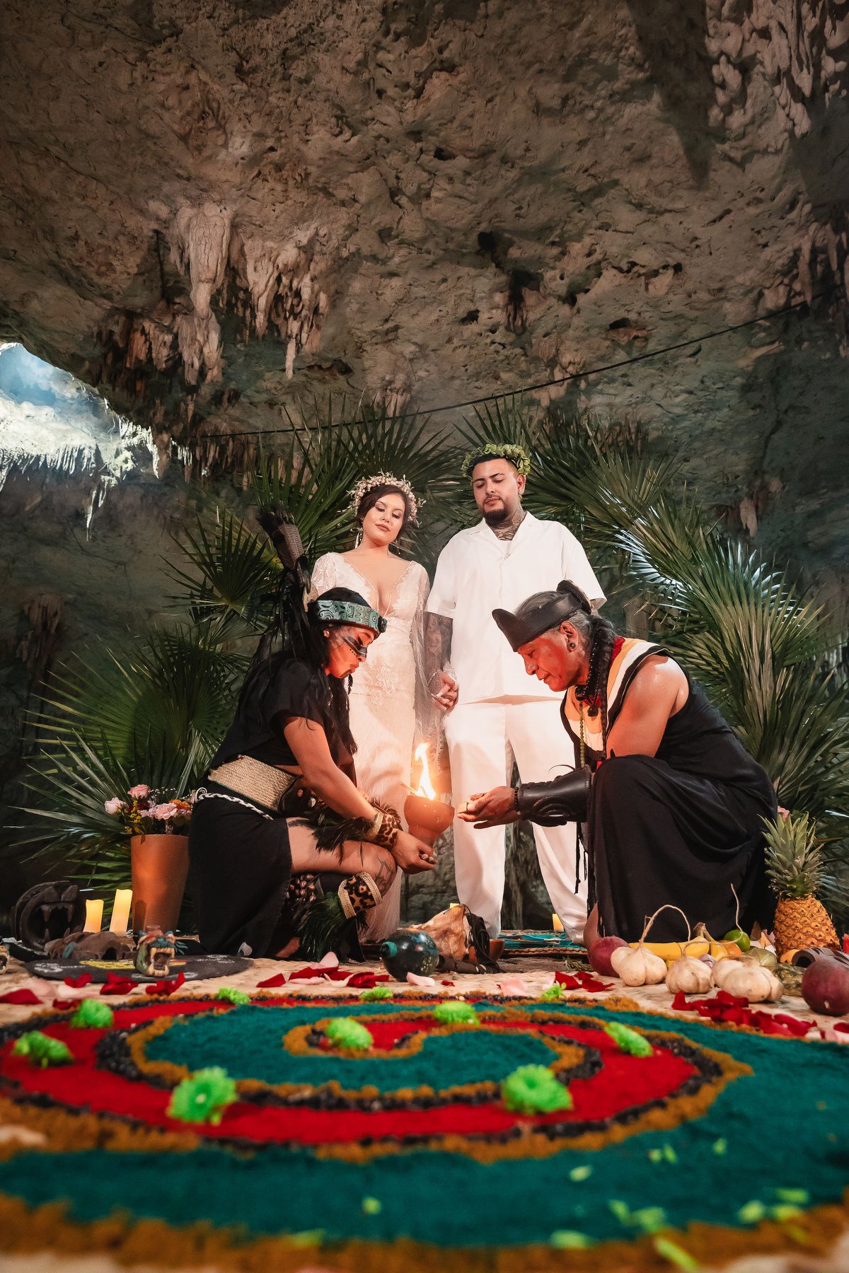 Colorful tropical ceremony setup in a cave with fruit and floral arrangements.