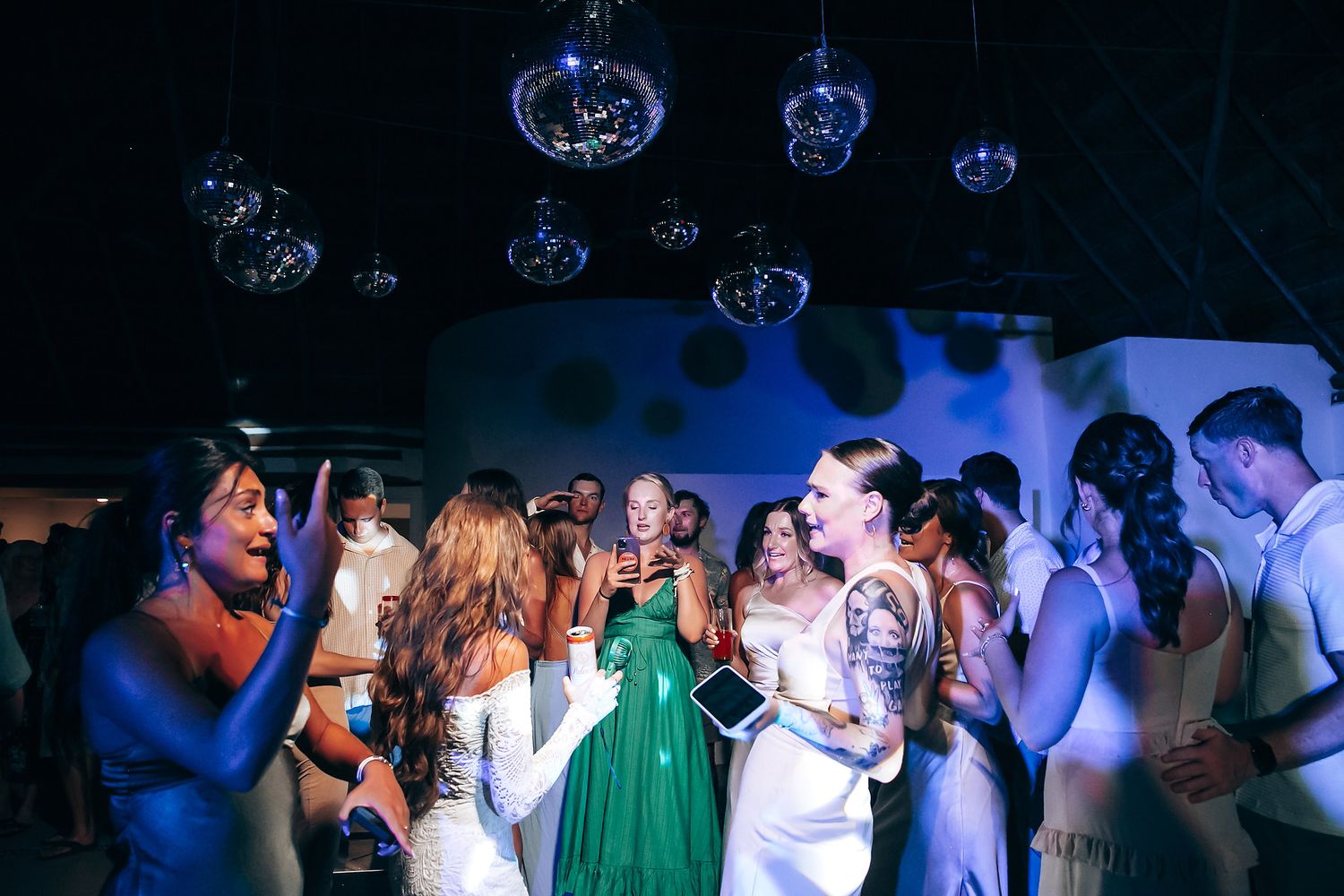 Wedding reception dance floor filled with celebrating guests under blue lighting.