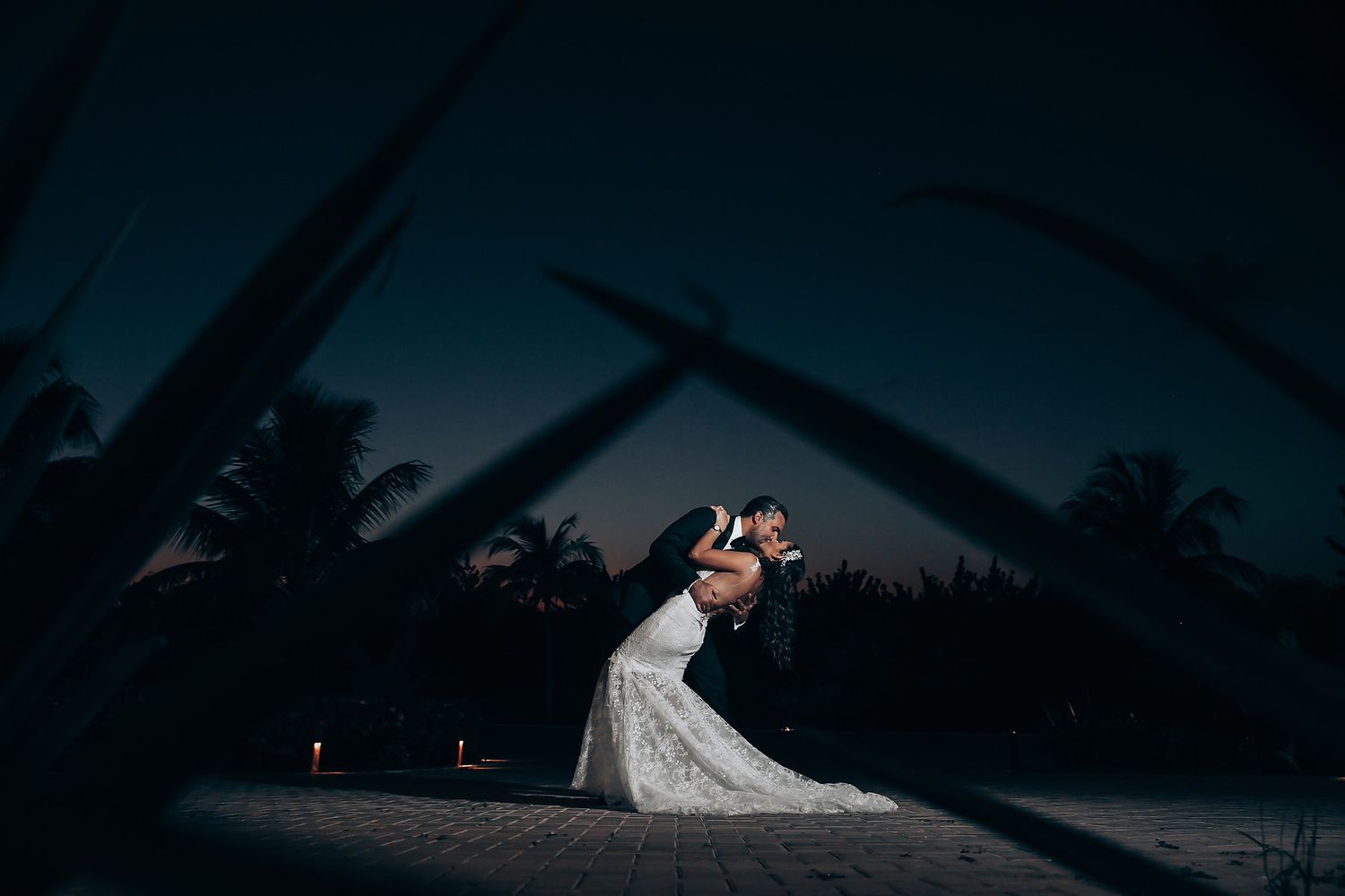 Silhouetted wedding scene against a dramatic sunset sky by the ocean.