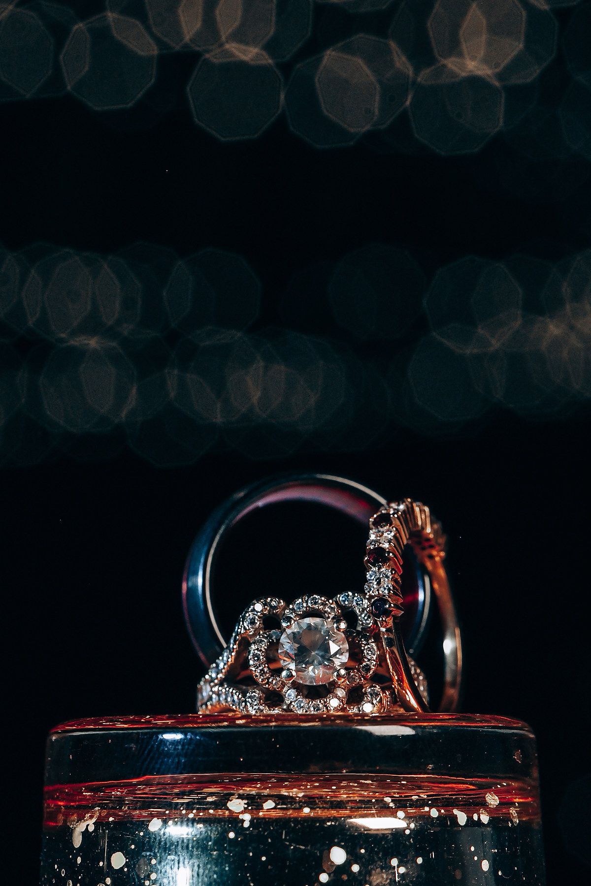 Crystal studded crown rests on a dark surface with bokeh lights in the background creating a magical atmosphere.
