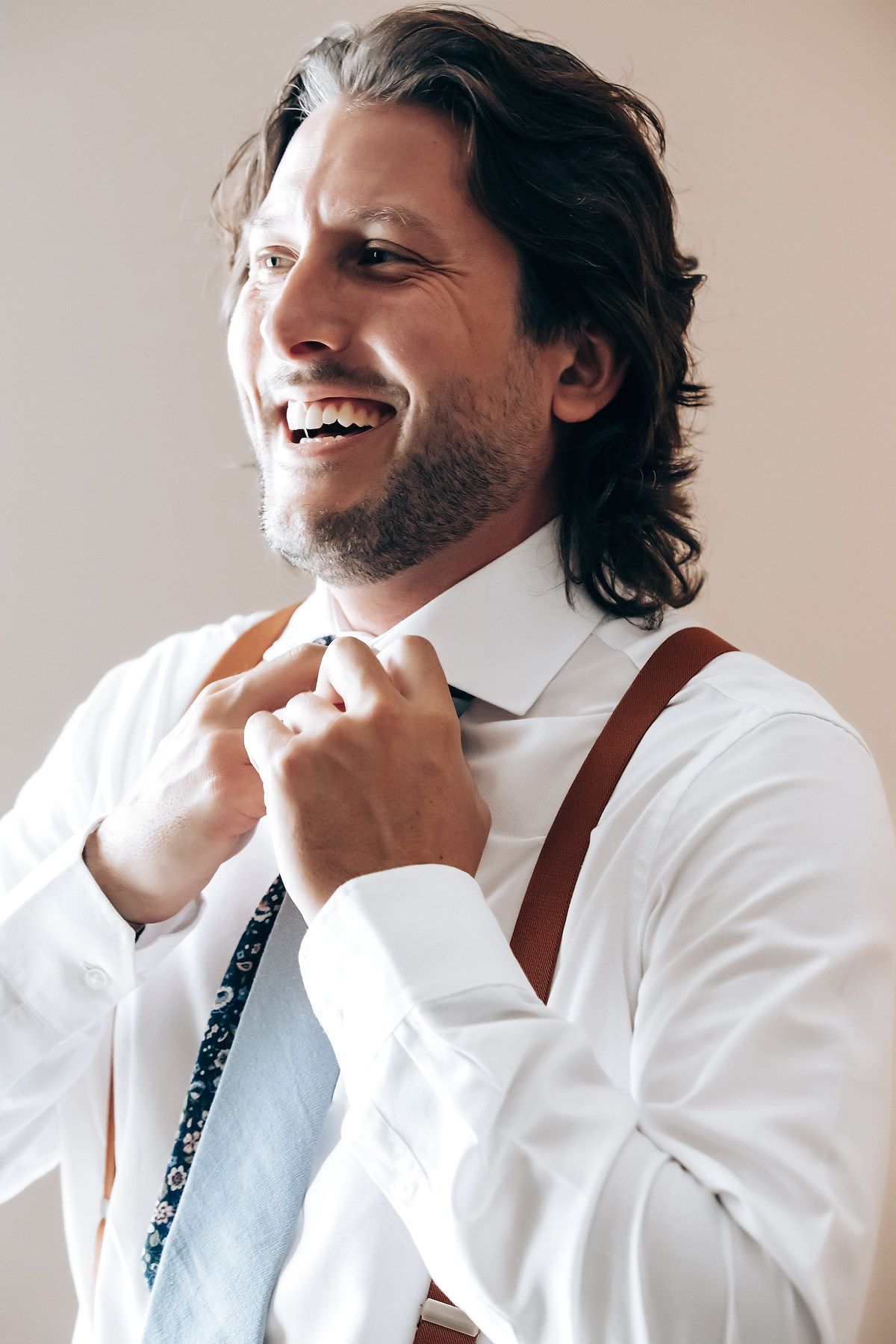A series of candid photos showing someone in a white shirt and suspenders laughing and smiling while touching their chin.