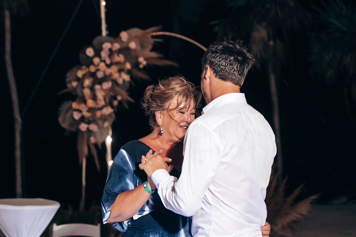 Intimate first dance moment at a dimly lit wedding reception with decorative lighting.
