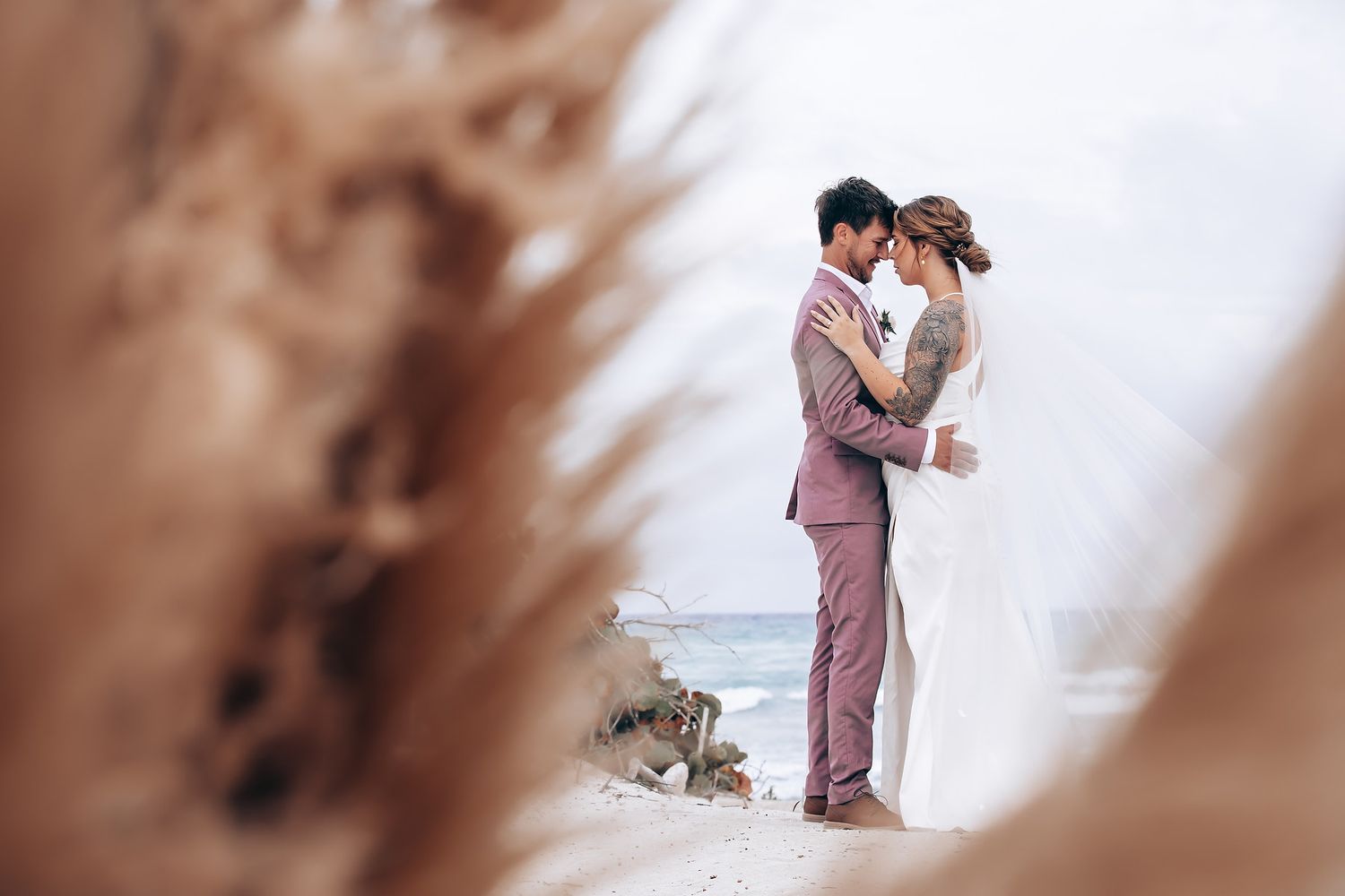 A romantic beach wedding ceremony at sunset with floral arrangements and palm trees.