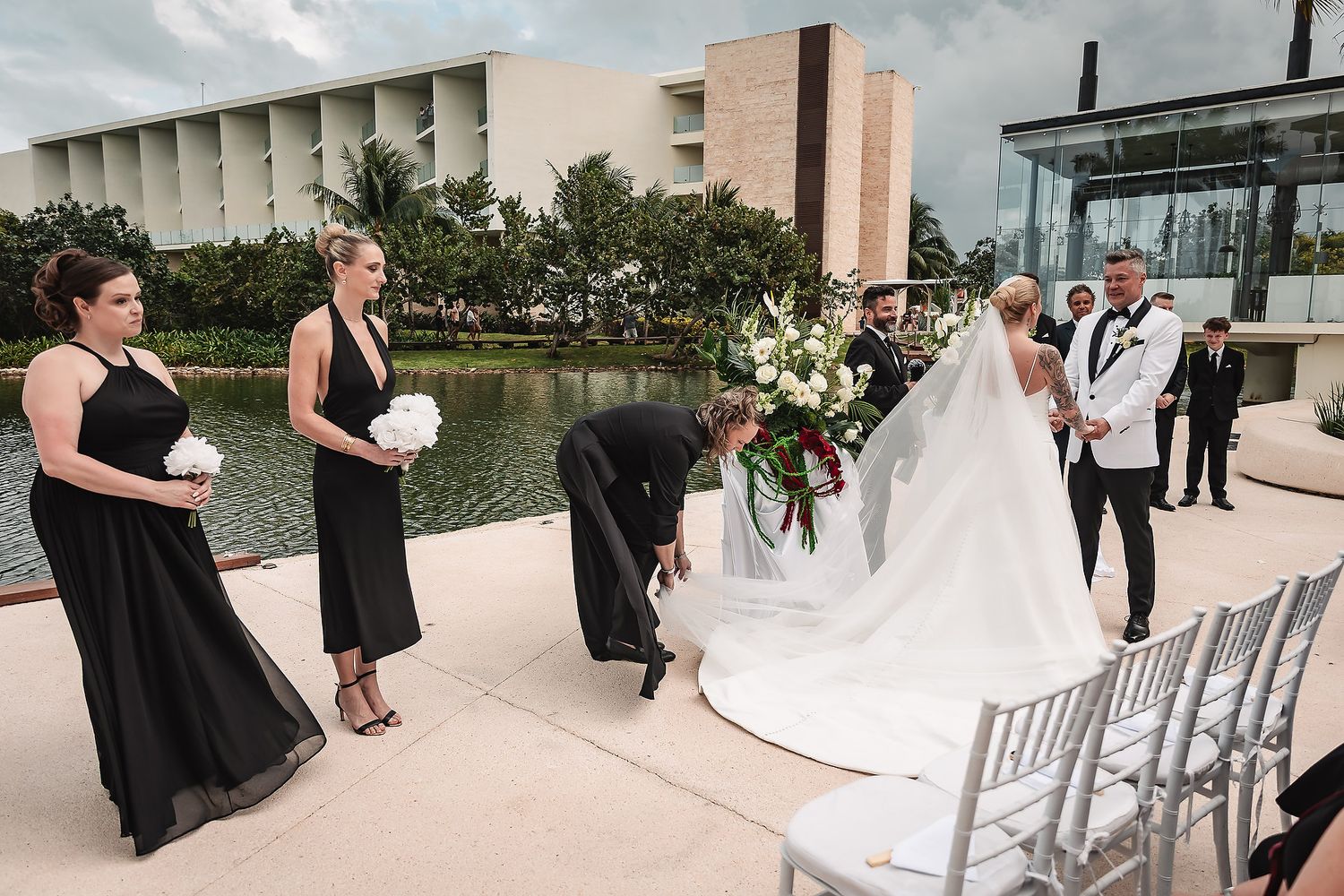 Wedding guests seated in white chairs at an outdoor ceremony venue with modern architecture.