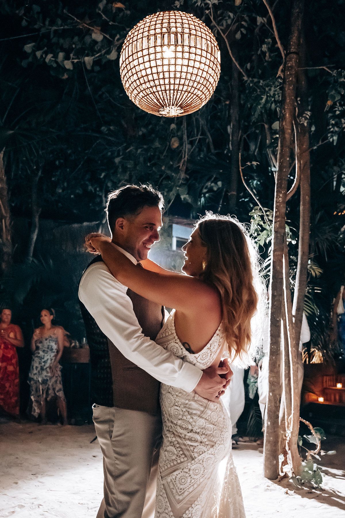 A couple shares their first dance under a sparkling disco ball at an outdoor wedding reception.