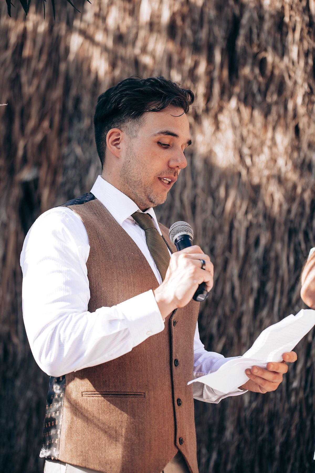 Wedding speech being delivered outdoors against a natural backdrop.