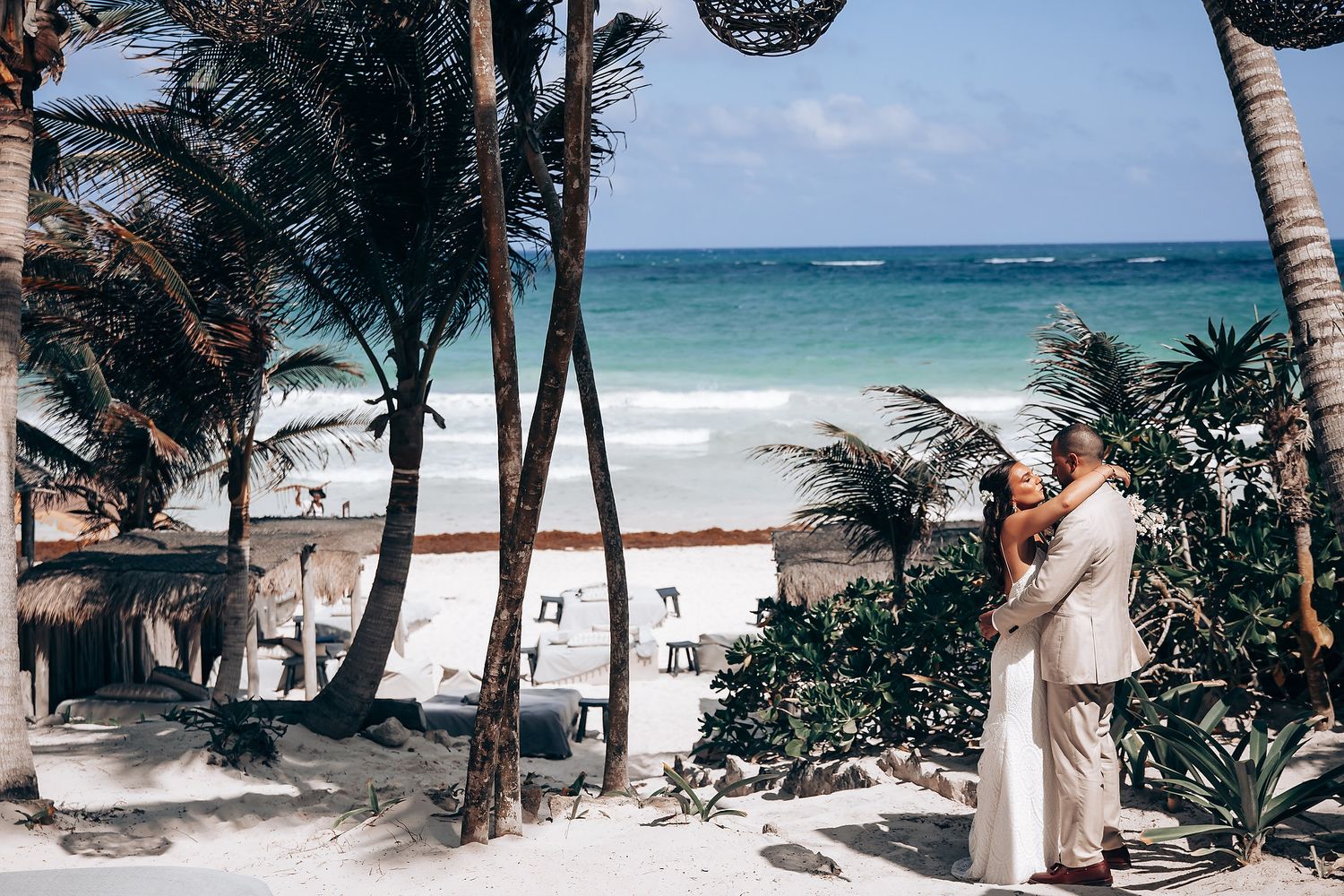 Panoramic view of a tropical beach wedding setting with palm trees and ocean backdrop.