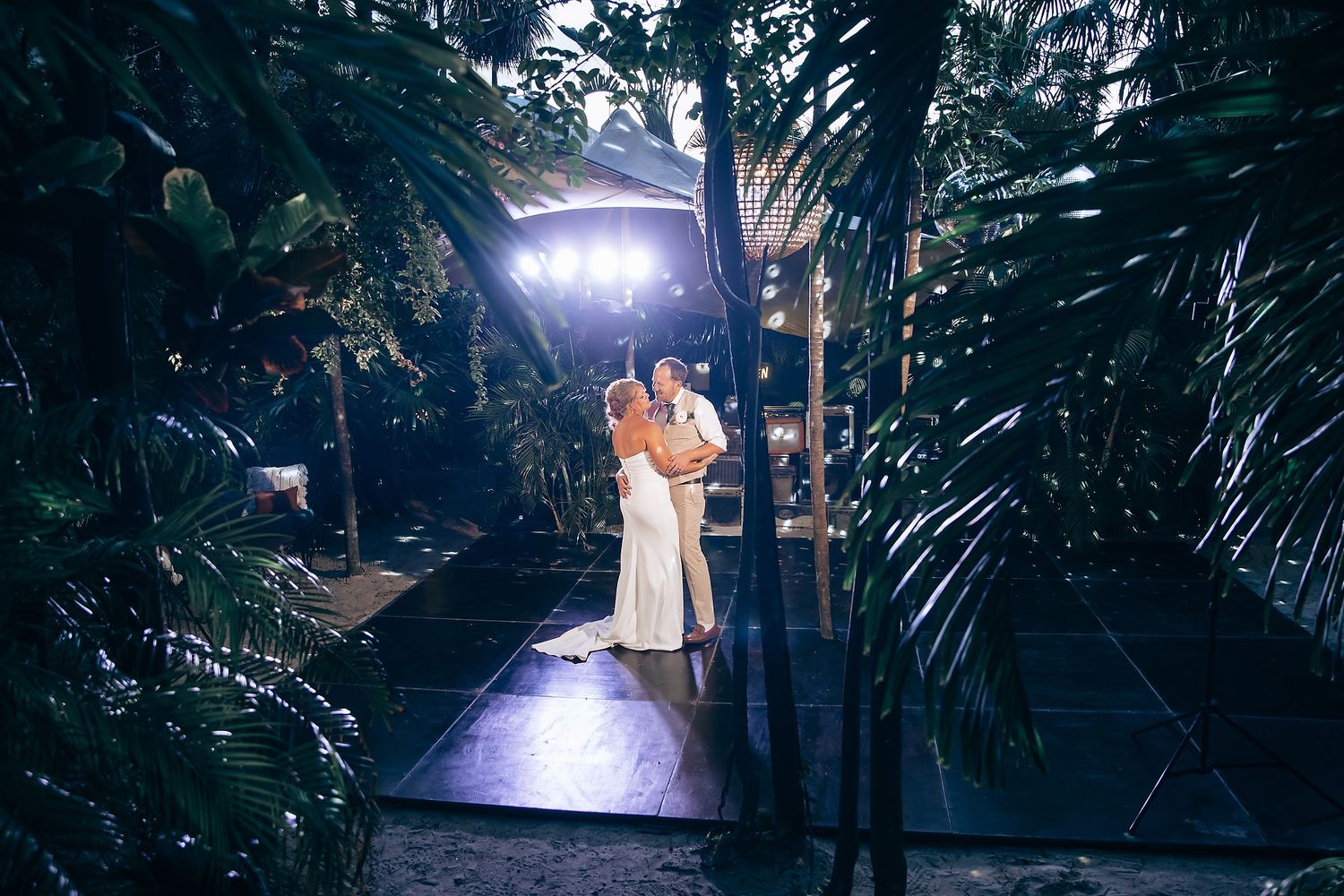 Dramatic spotlit dance moment at an outdoor evening wedding reception.