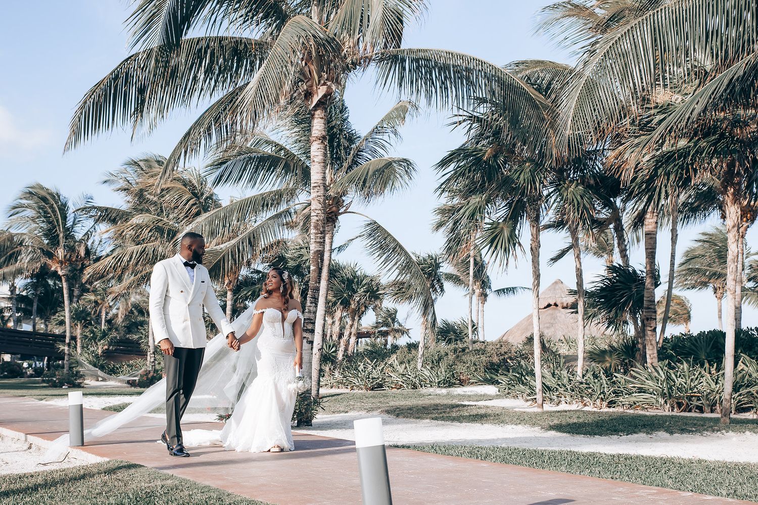 Tropical wedding venue with palm trees lining a white ceremony walkway.