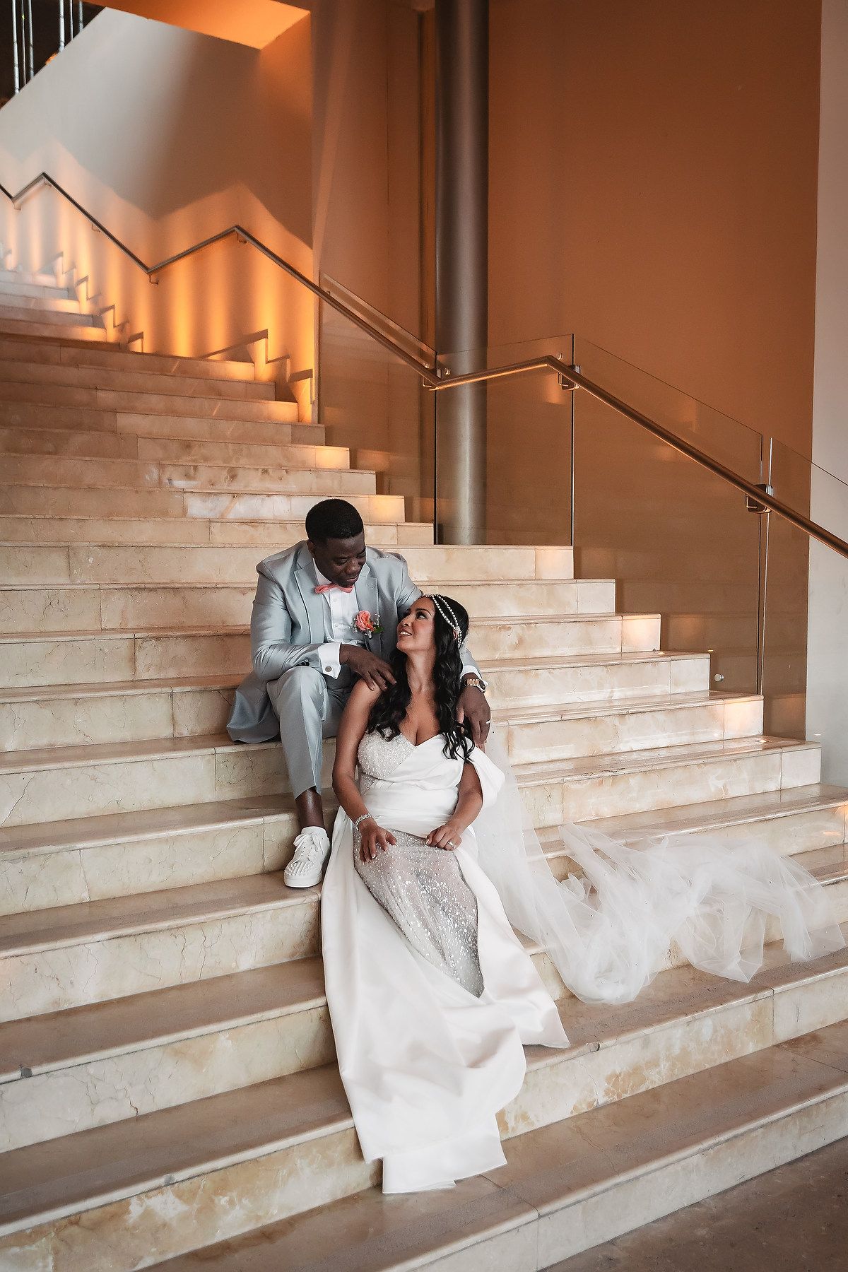 A romantic moment captured on elegant marble stairs in an indoor venue.