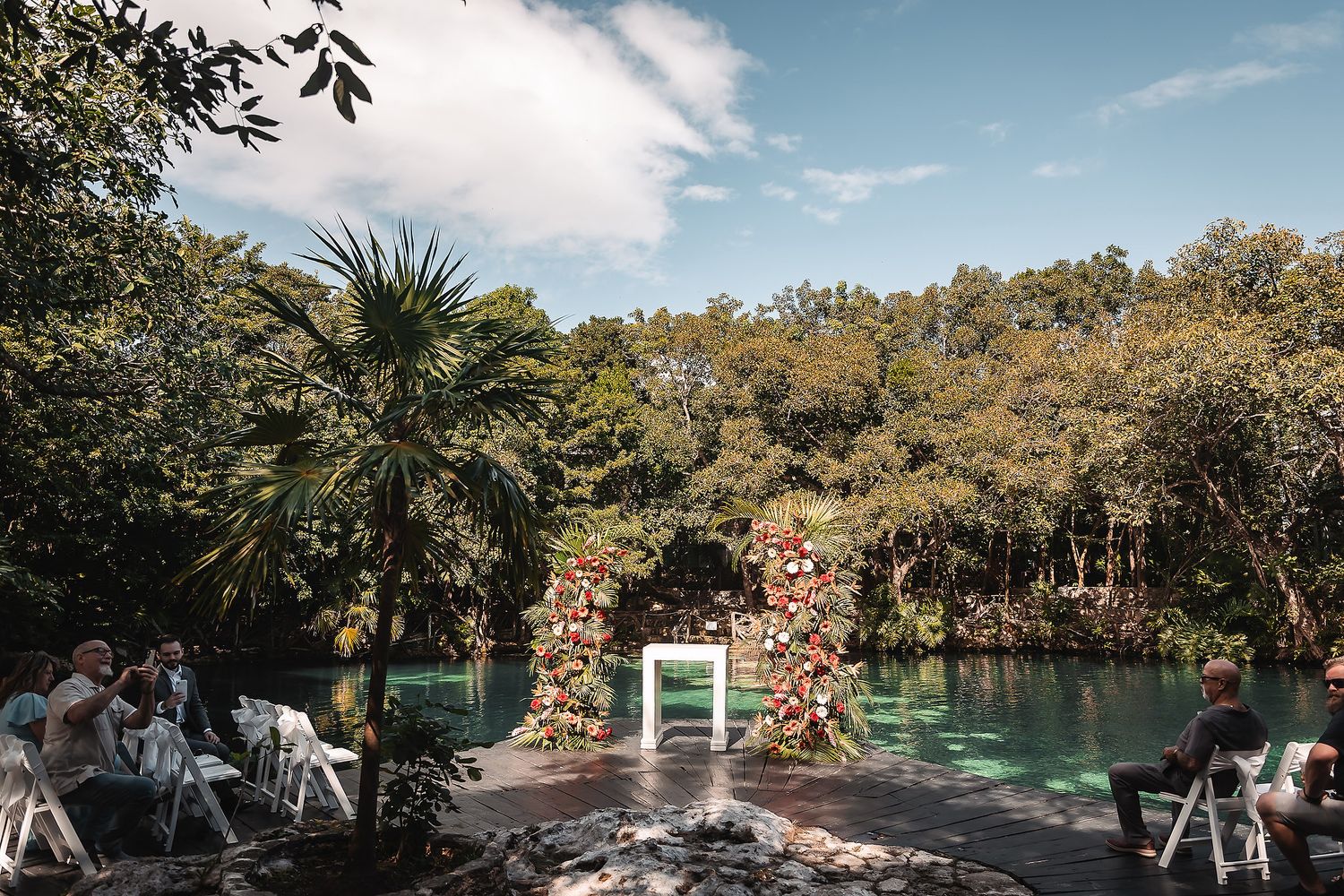 Outdoor wedding venue with tropical landscaping and natural stone walkway under blue skies.