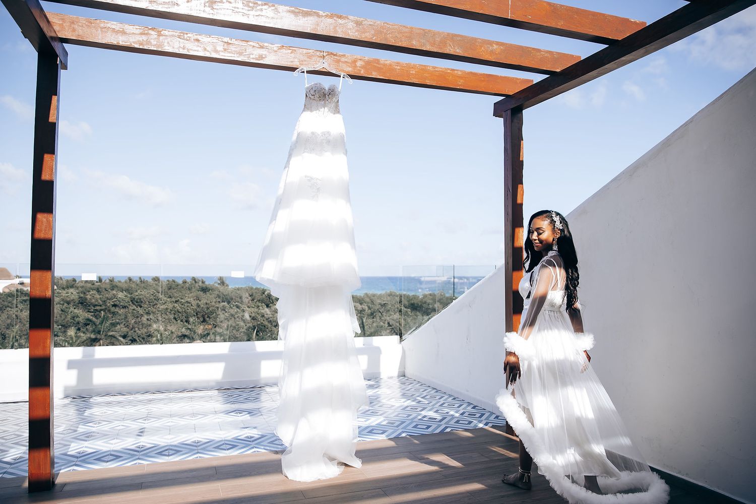 Wedding dress flowing in the breeze against white pillars and blue sky.