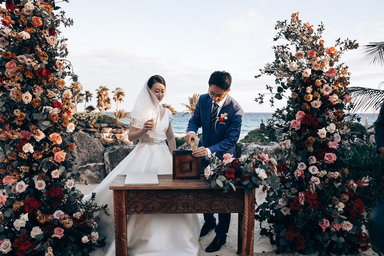 Wedding ceremony setup with floral arch and rustic wooden table outdoors.