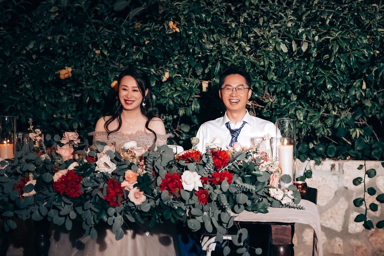 Wedding reception table decorated with lush floral arrangements and greenery.