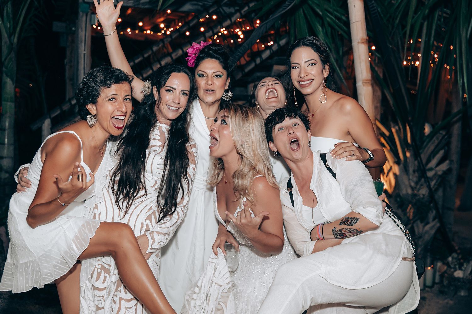 A group of people dressed in white celebrate and dance together at a lively party.