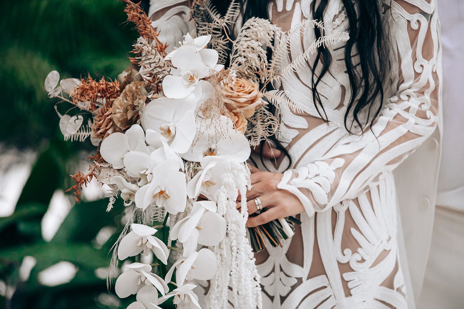 Elegant white orchid bouquet with cascading flowers against a natural green background.