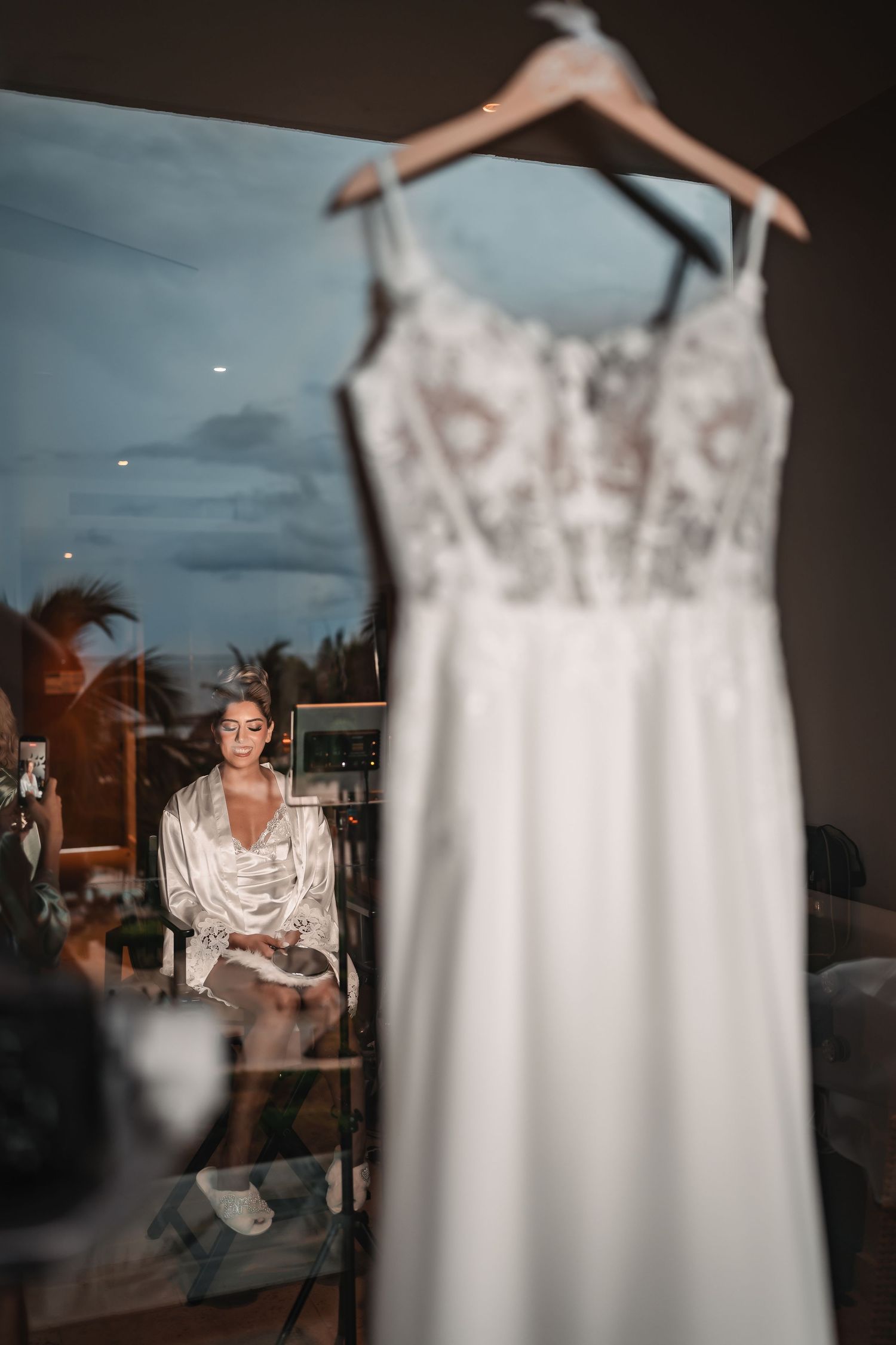 White lace wedding dress displayed on hanger against neutral background.