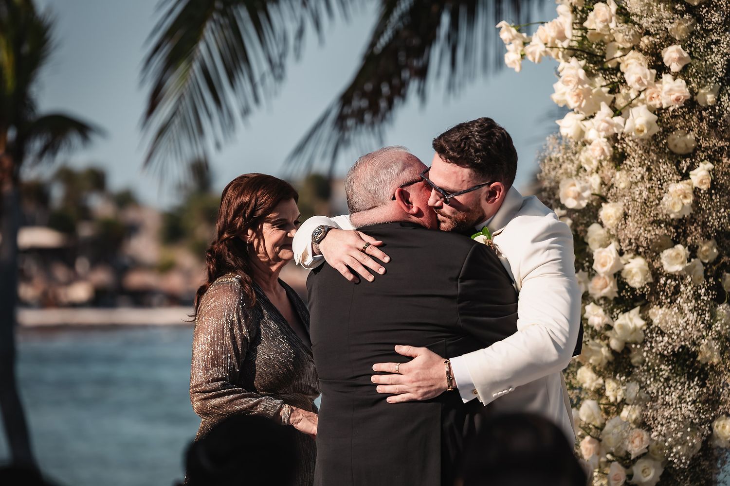 Emotional embraces between wedding guests at a beachside celebration.