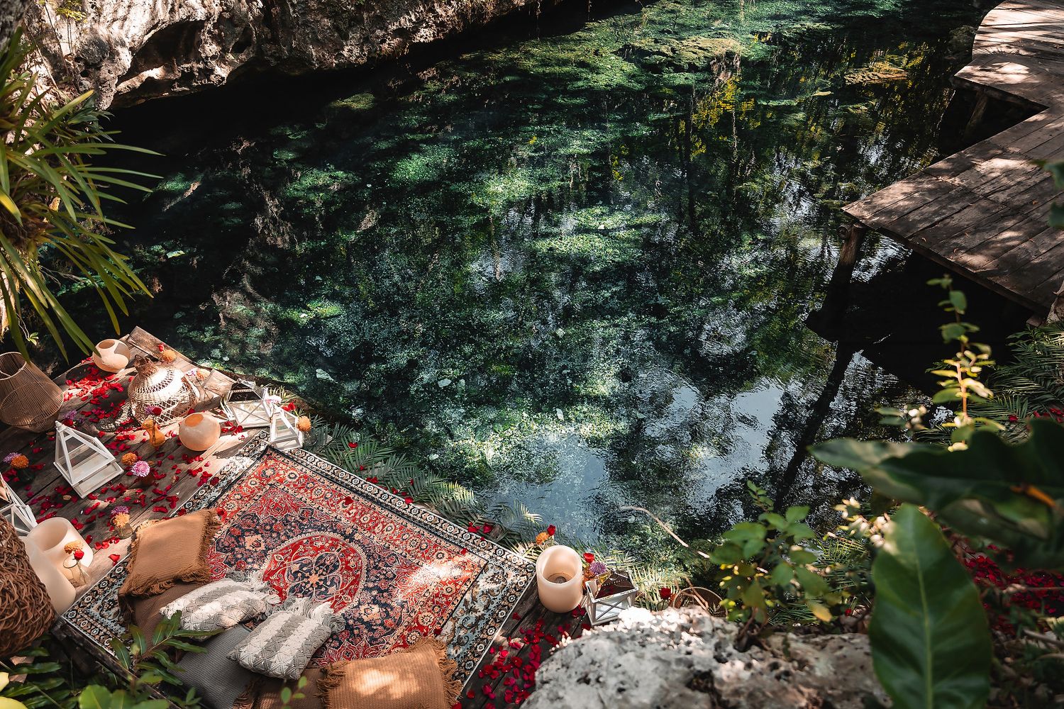 Rustic picnic setup with oriental rugs overlooking crystal clear cenote waters.