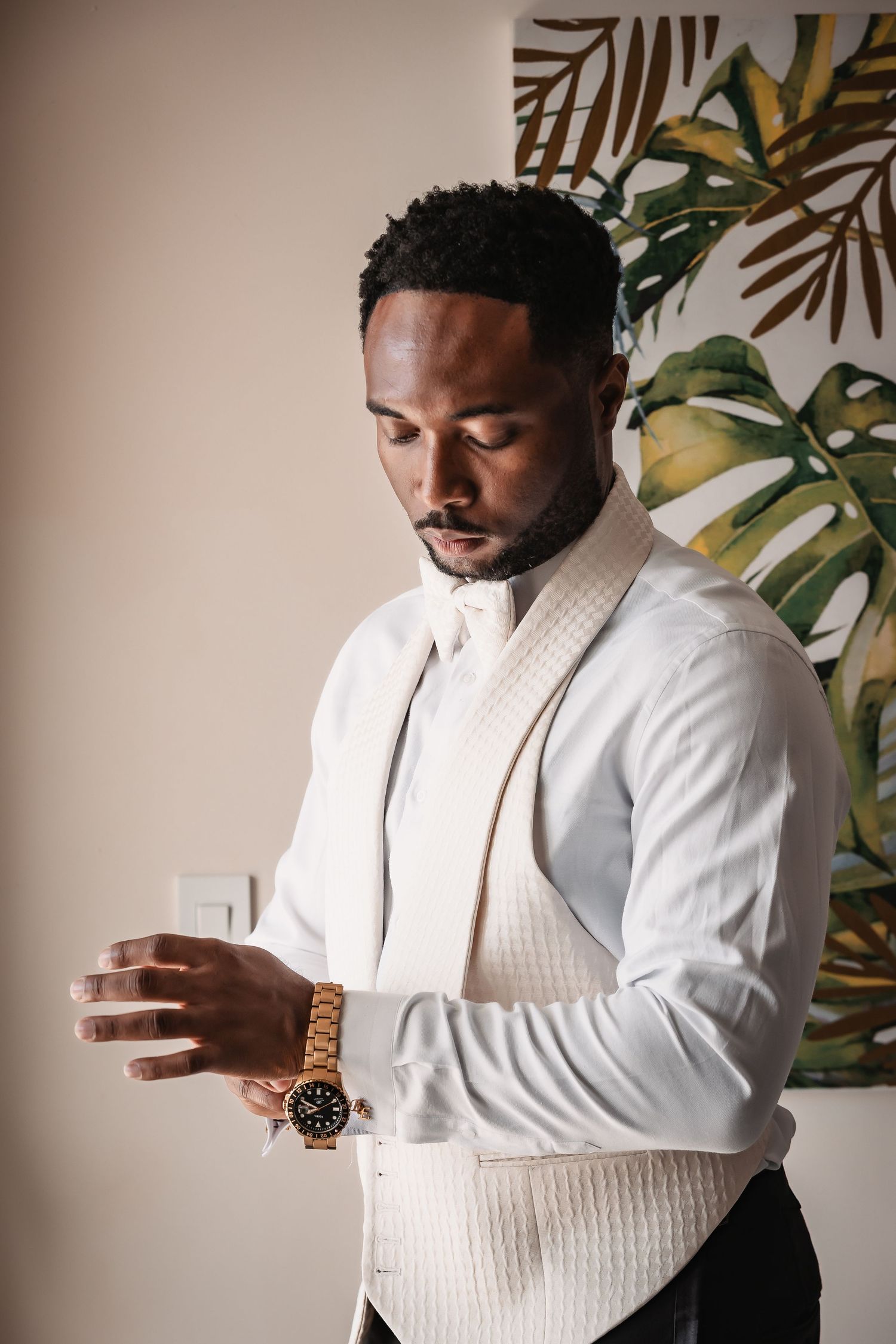 Getting ready moments captured against a tropical leaf wallpaper background.