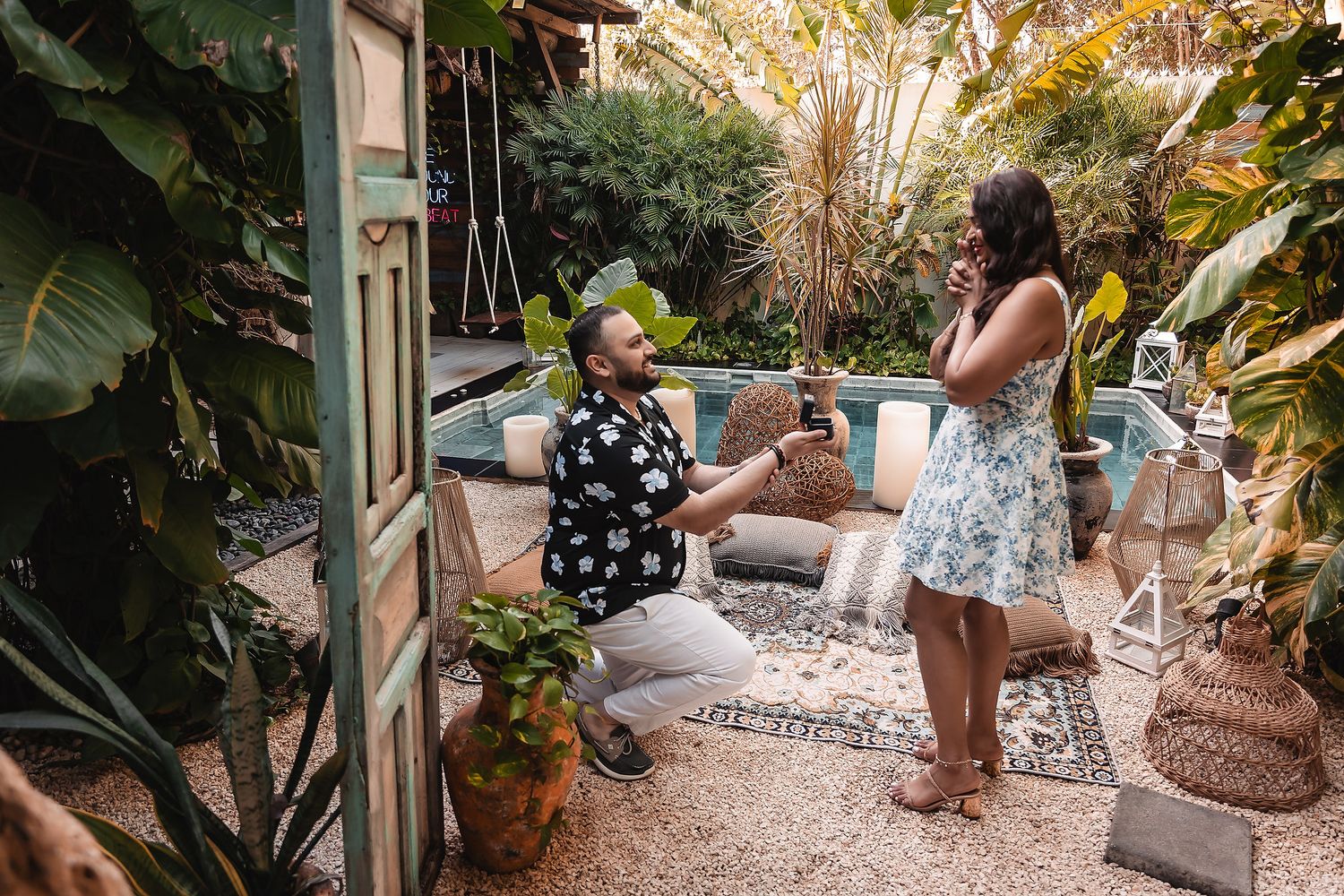 Garden party scene with tropical plants and outdoor furniture.