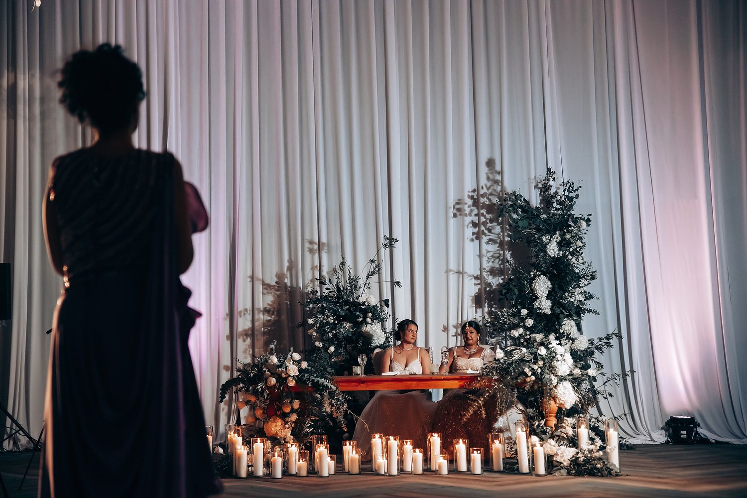 Silhouette against dramatic wedding reception decor with candlelight and floral arrangements.