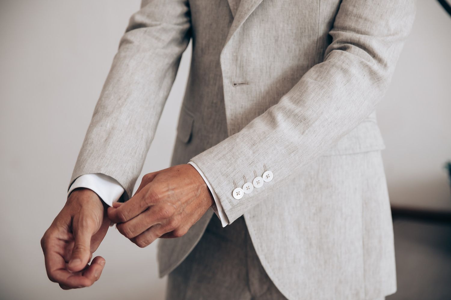 Close-up view of a person wearing a light gray linen suit jacket with textured fabric details.