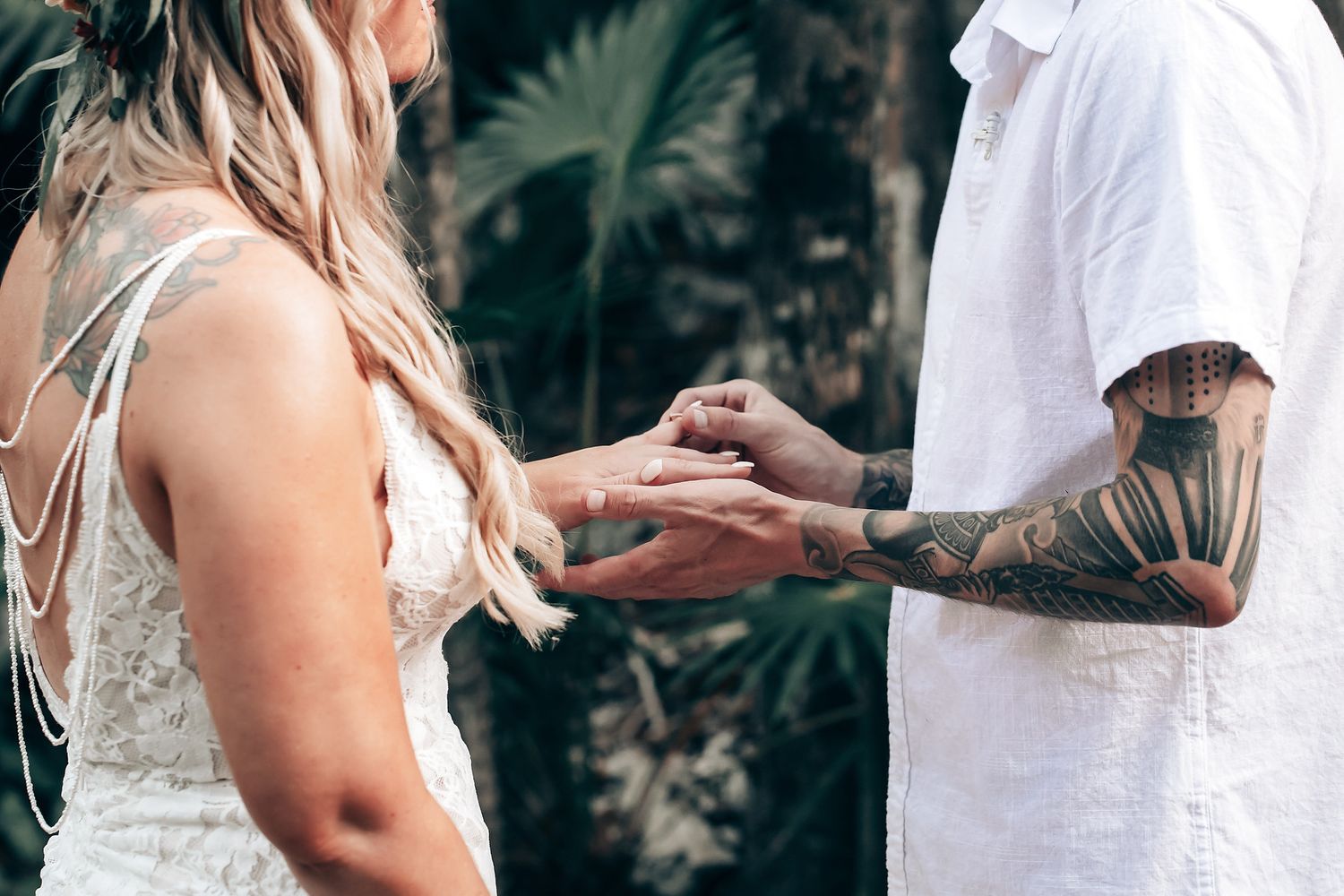 Couple holding hands in a natural outdoor setting with greenery in the background.