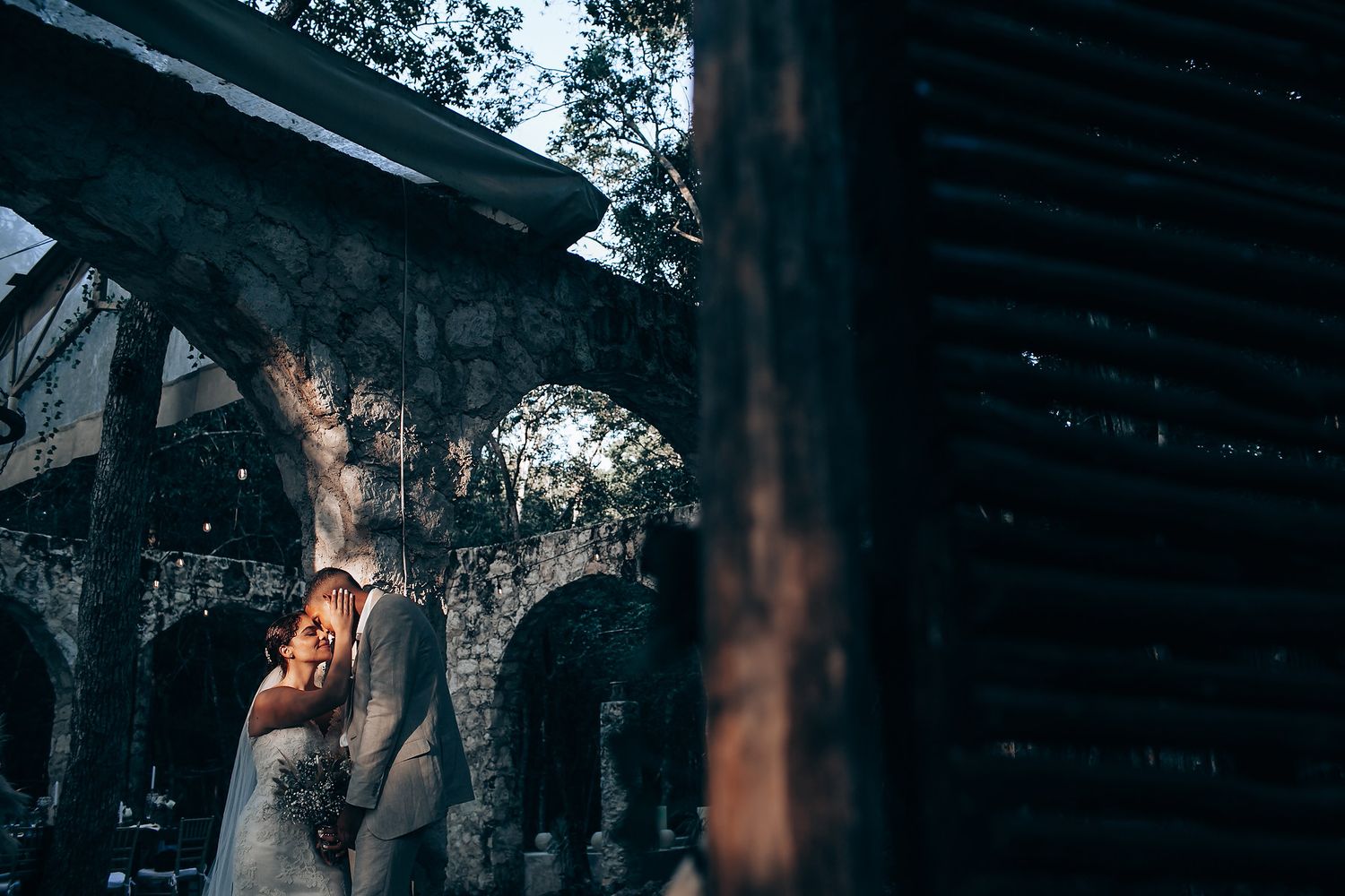 Moody wedding photography sequence showing silhouettes against stone walls in dramatic lighting.