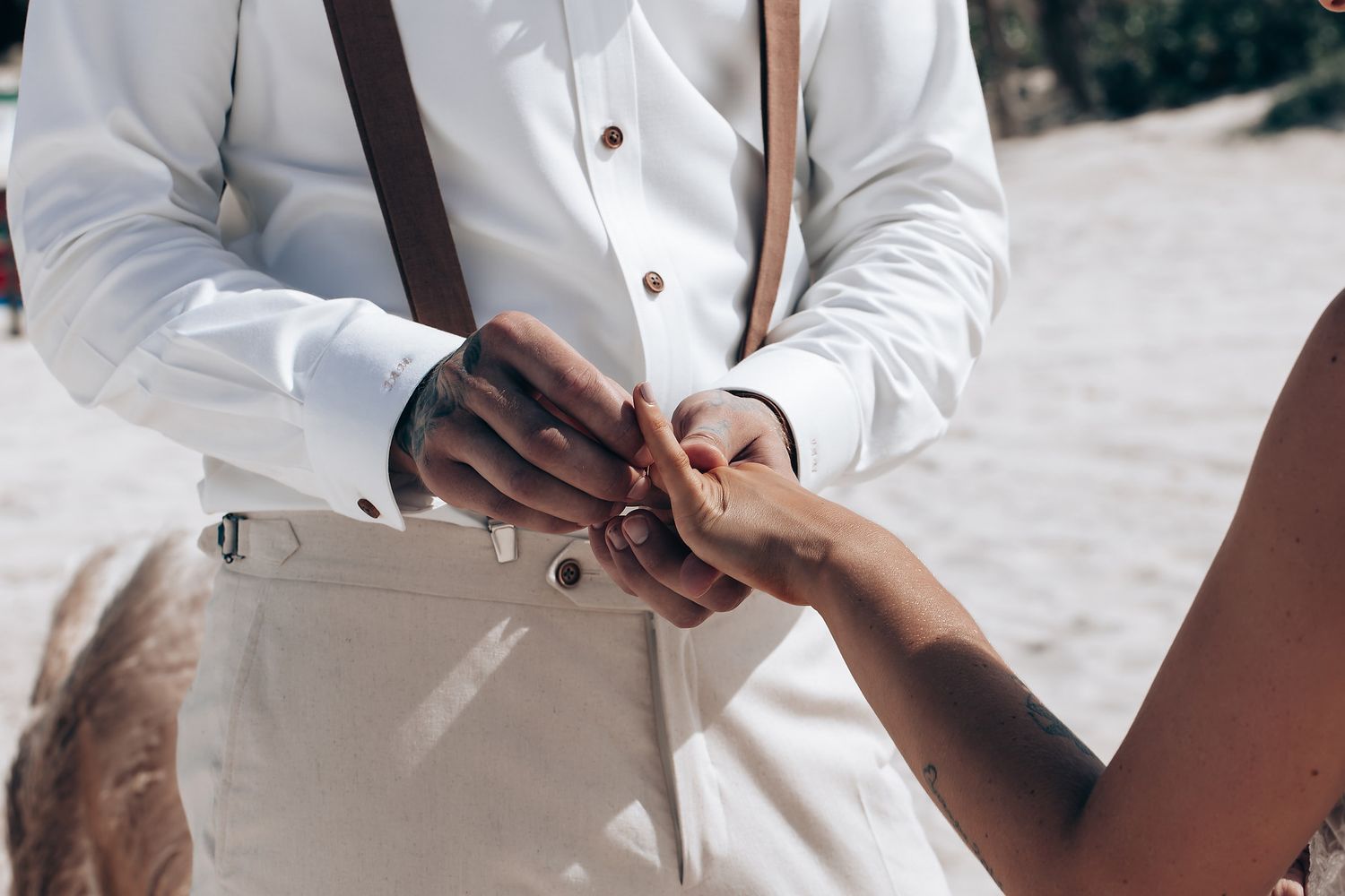 Close-up details of white wedding attire and accessories on a sunny day.