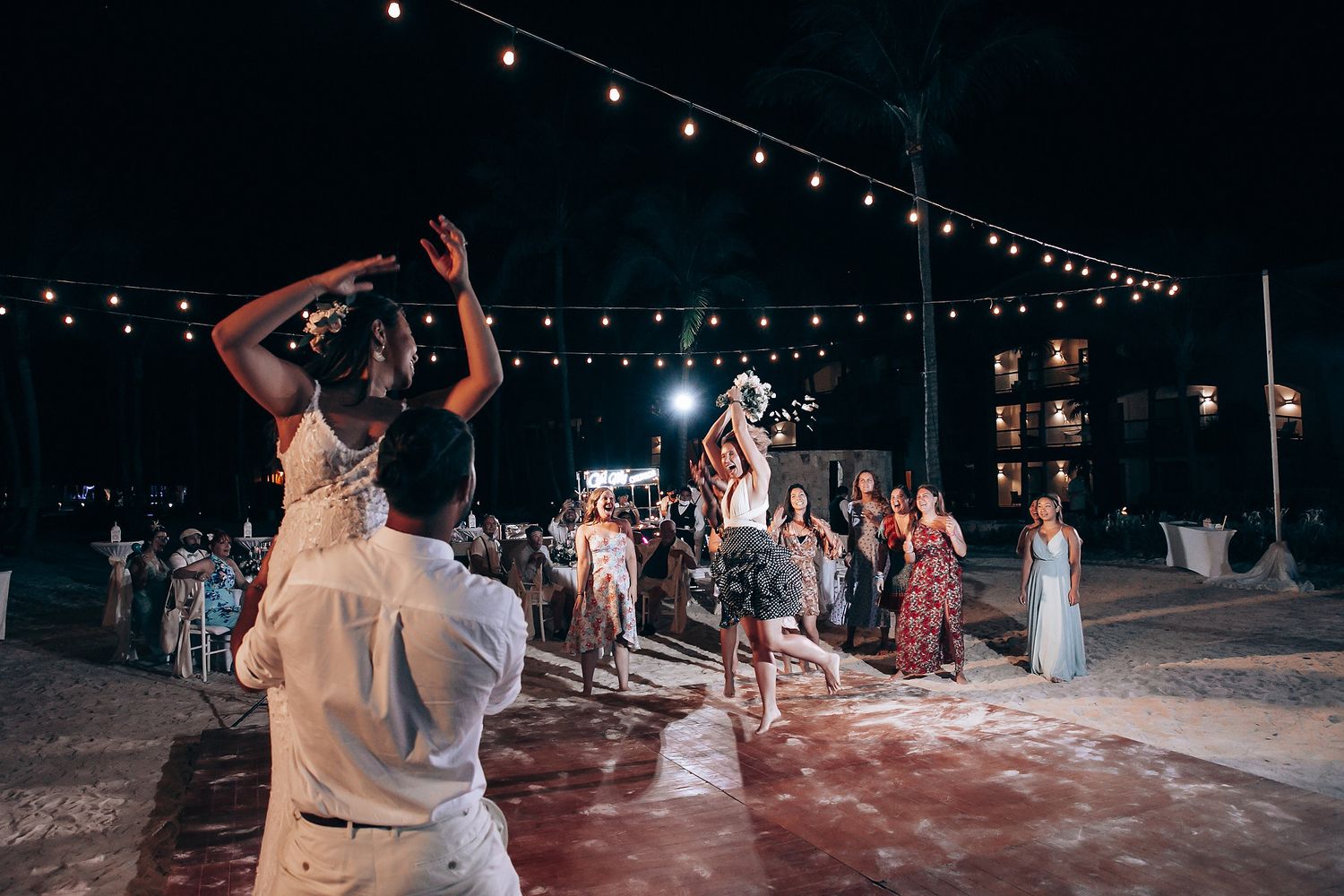 Wedding guests dancing on an illuminated outdoor dance floor at night.