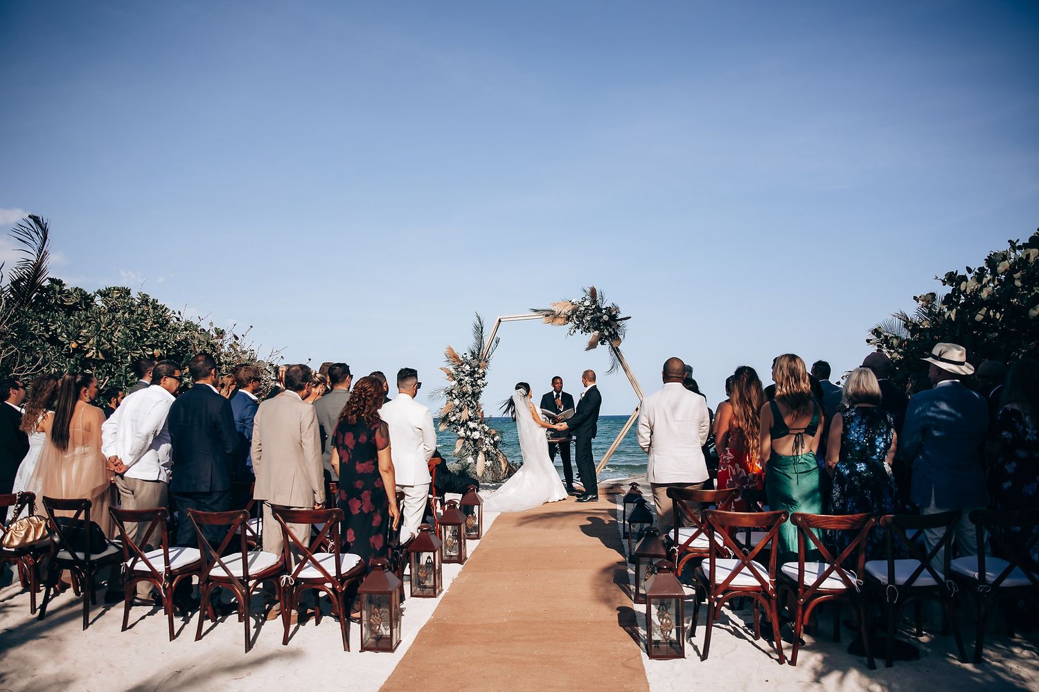 Outdoor beach wedding ceremony setup with white chairs and ocean backdrop.