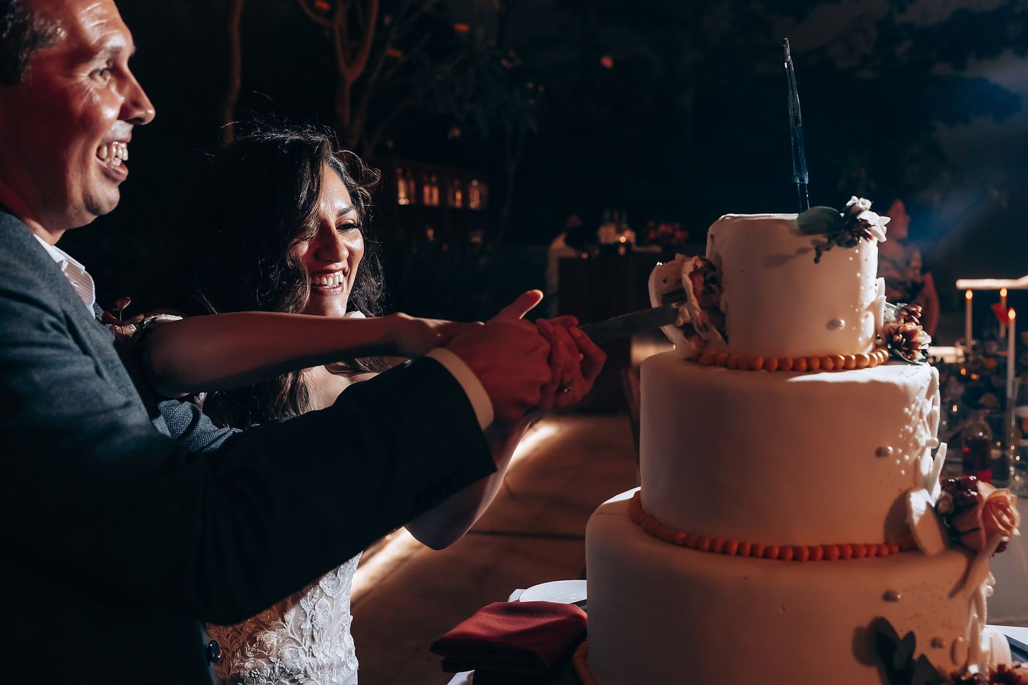A couple cuts into their three-tiered wedding cake during their reception celebration.