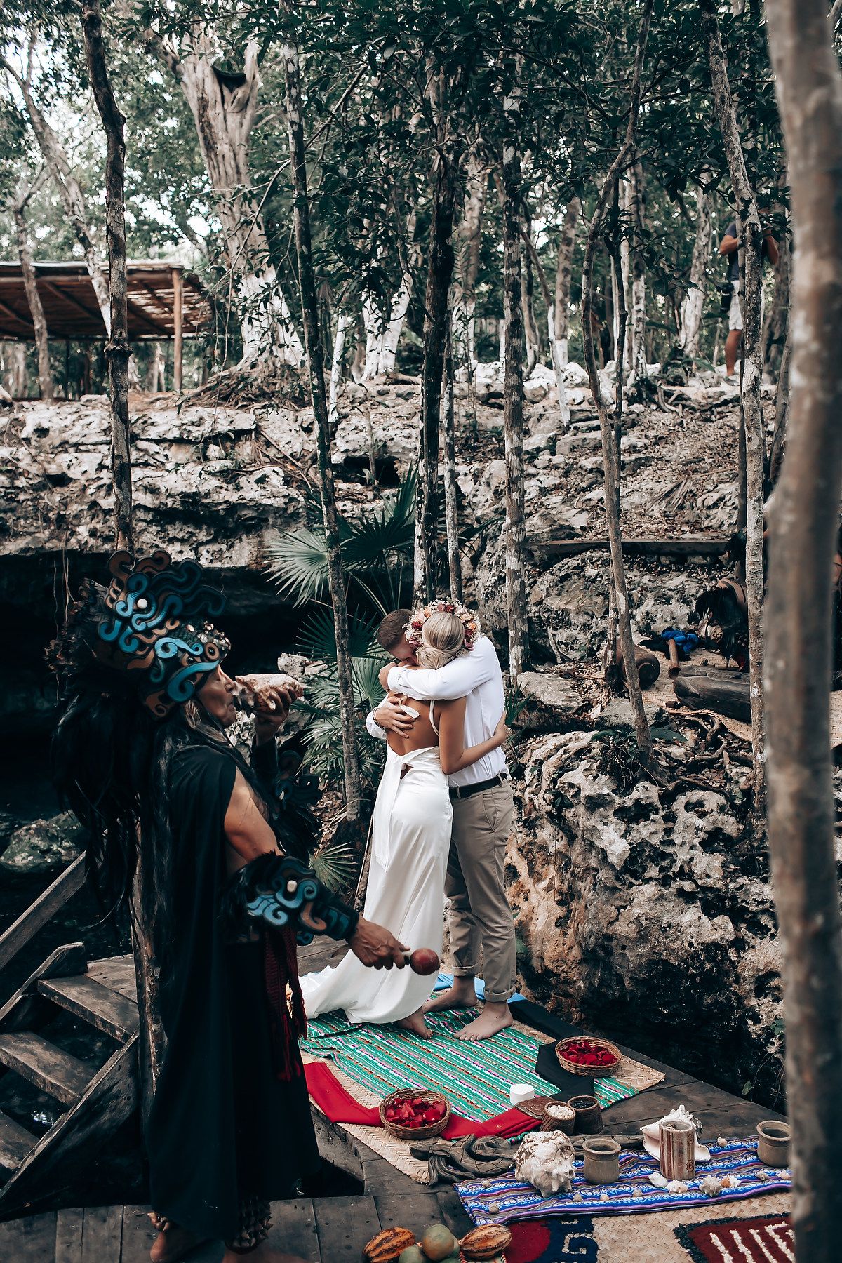 A couple shares an intimate moment during a photoshoot in a scenic forest setting.