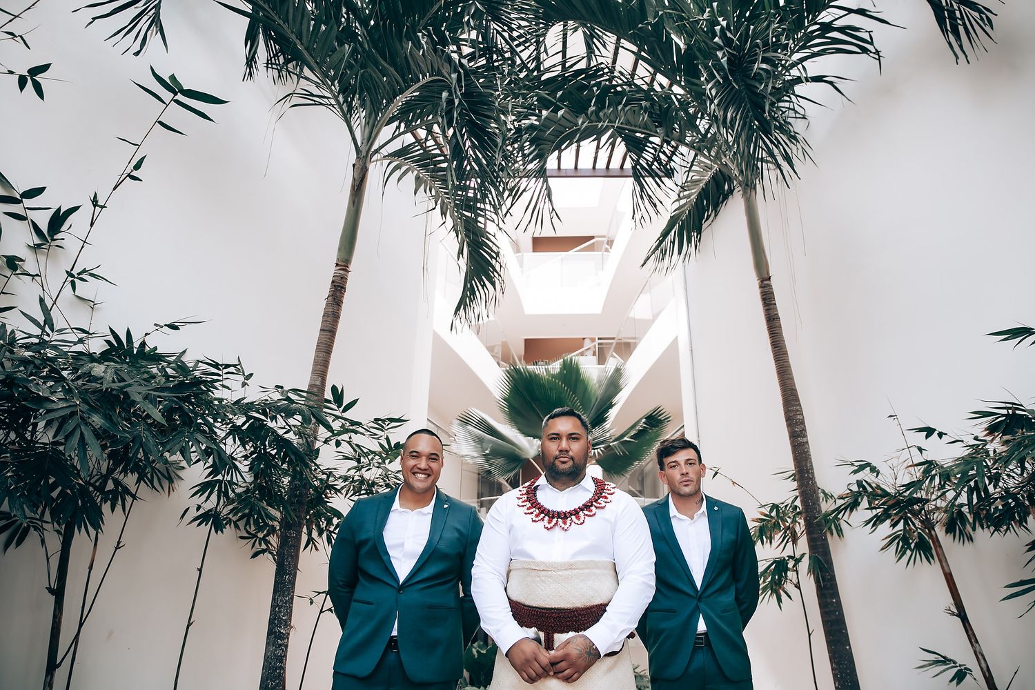 Tropical beach wedding ceremony setup with palm trees and white decor.